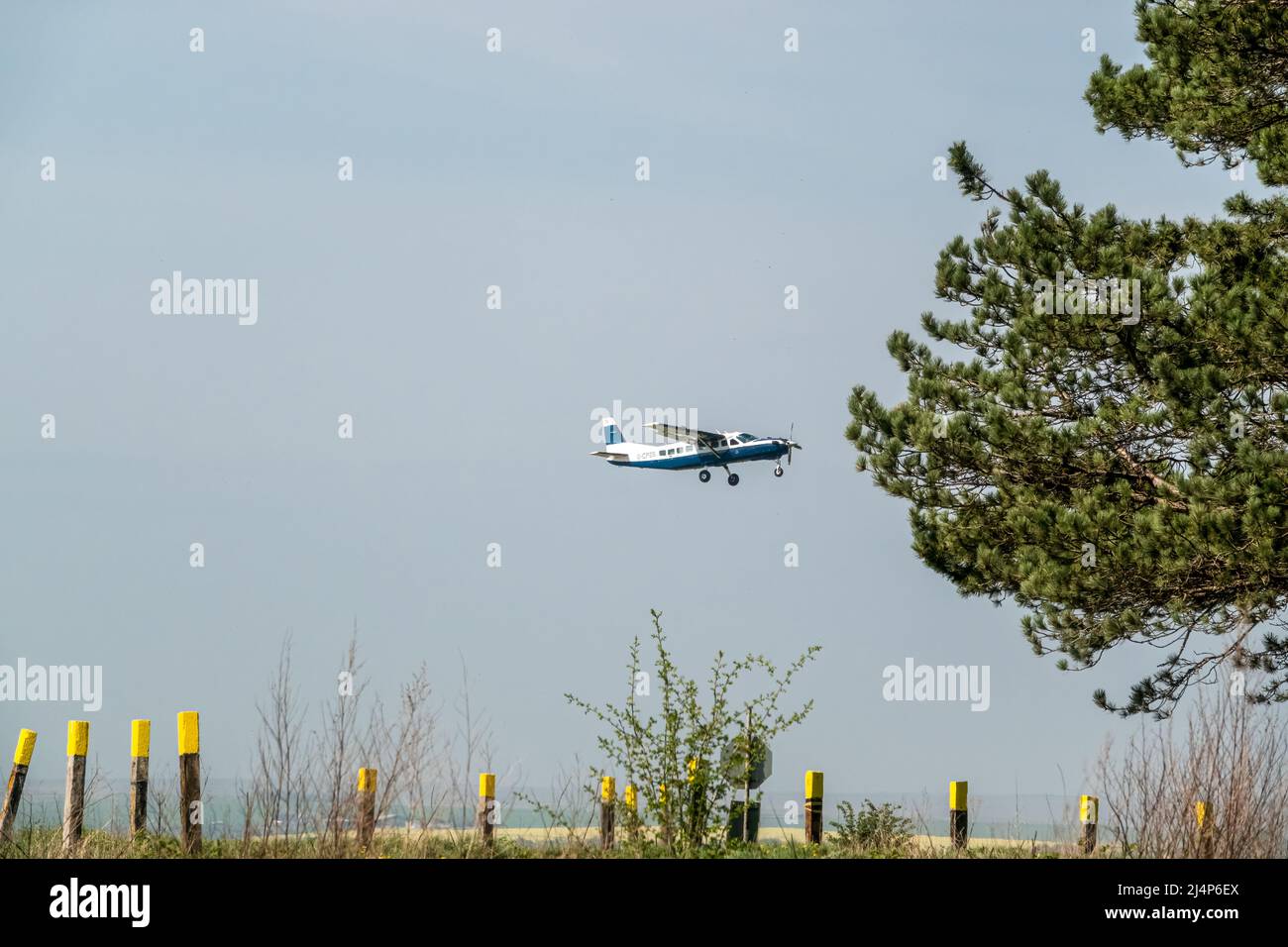 Cessna 208b Grand Caravan G-CPSS light aircraft ascending from a grass runway takeoff Stock Photo