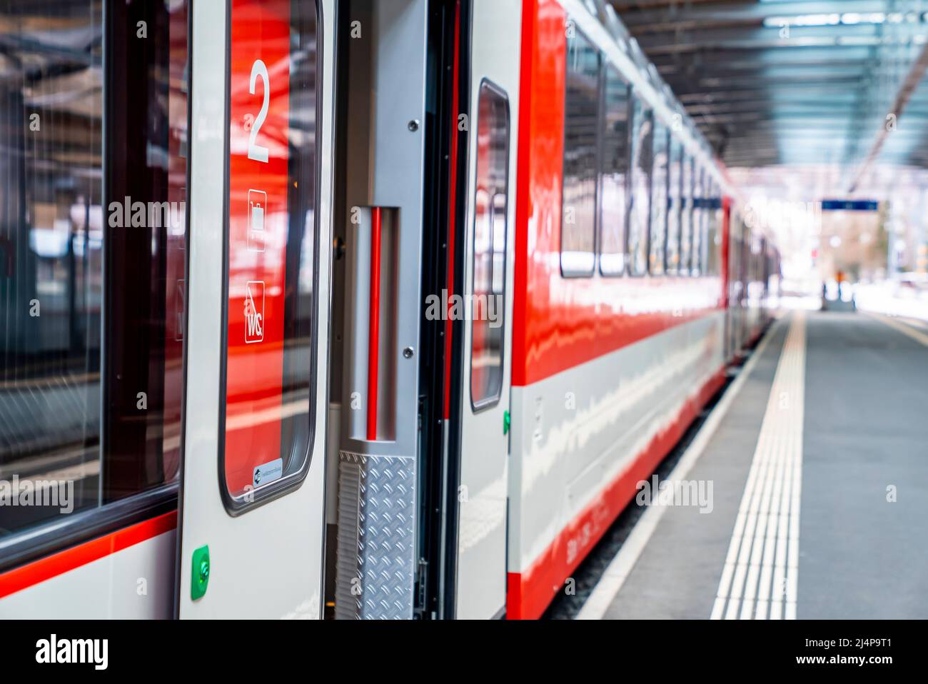 Open door of train arrived at platform on railroad station during sunny day Stock Photo