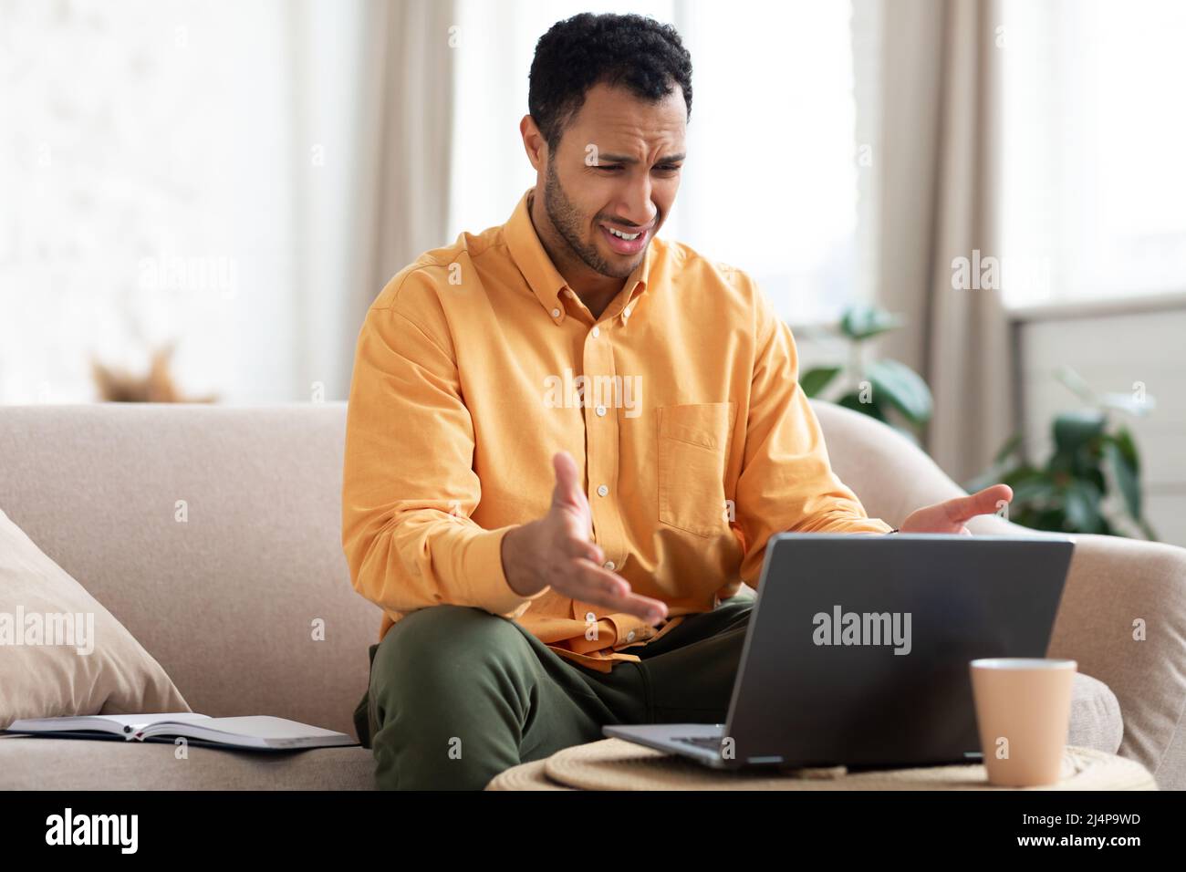 Confused Arab guy using laptop looking at screen Stock Photo