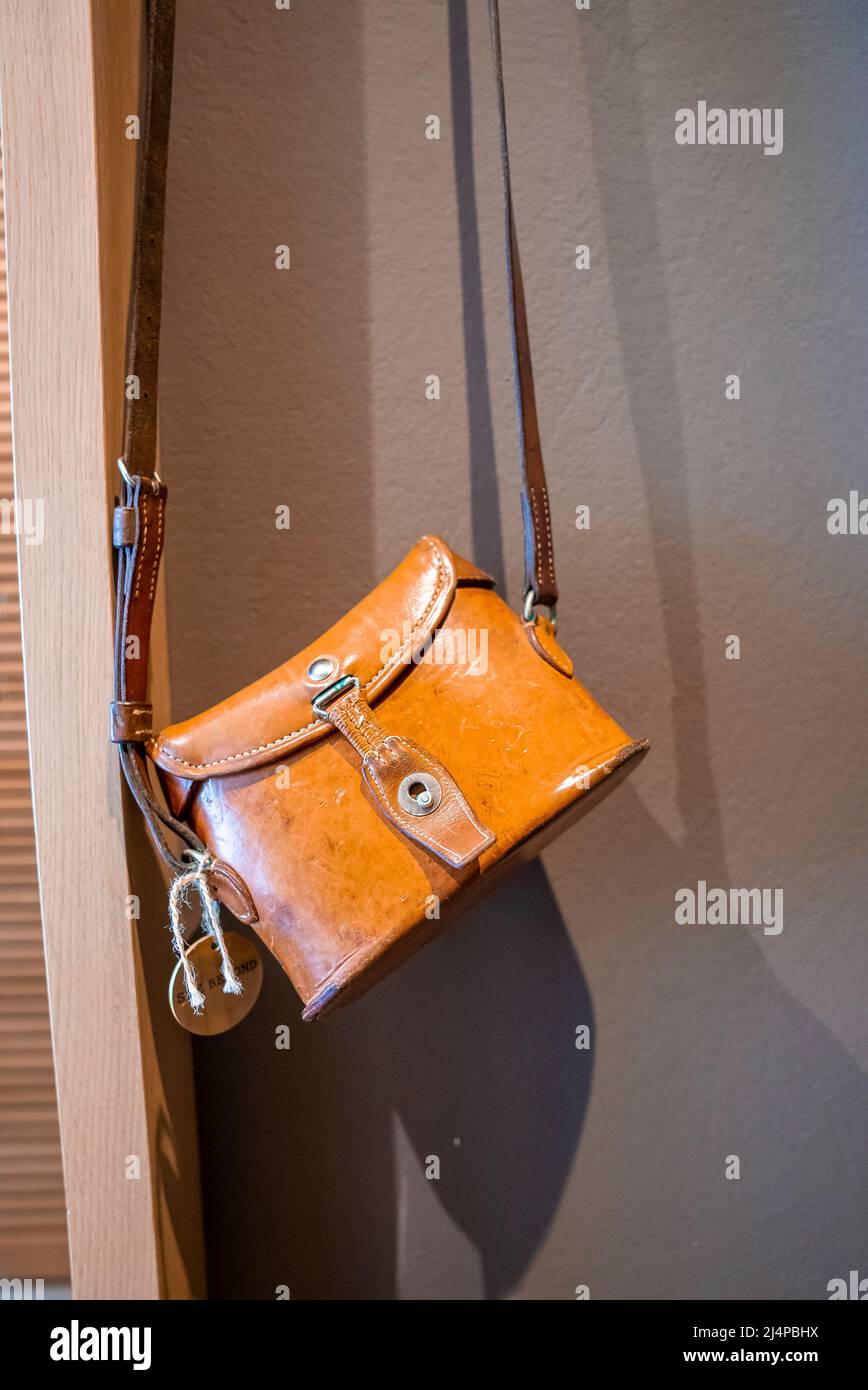 Close-up of yellow leather bag hanging against wall in empty hotel room Stock Photo