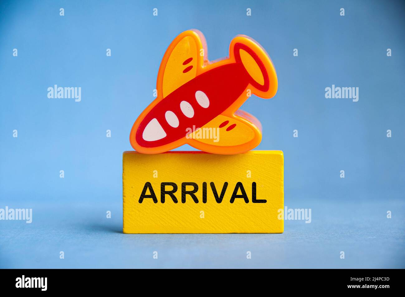 Arrival text on yellow wooden block with toy plane on top. Travelling concept Stock Photo
