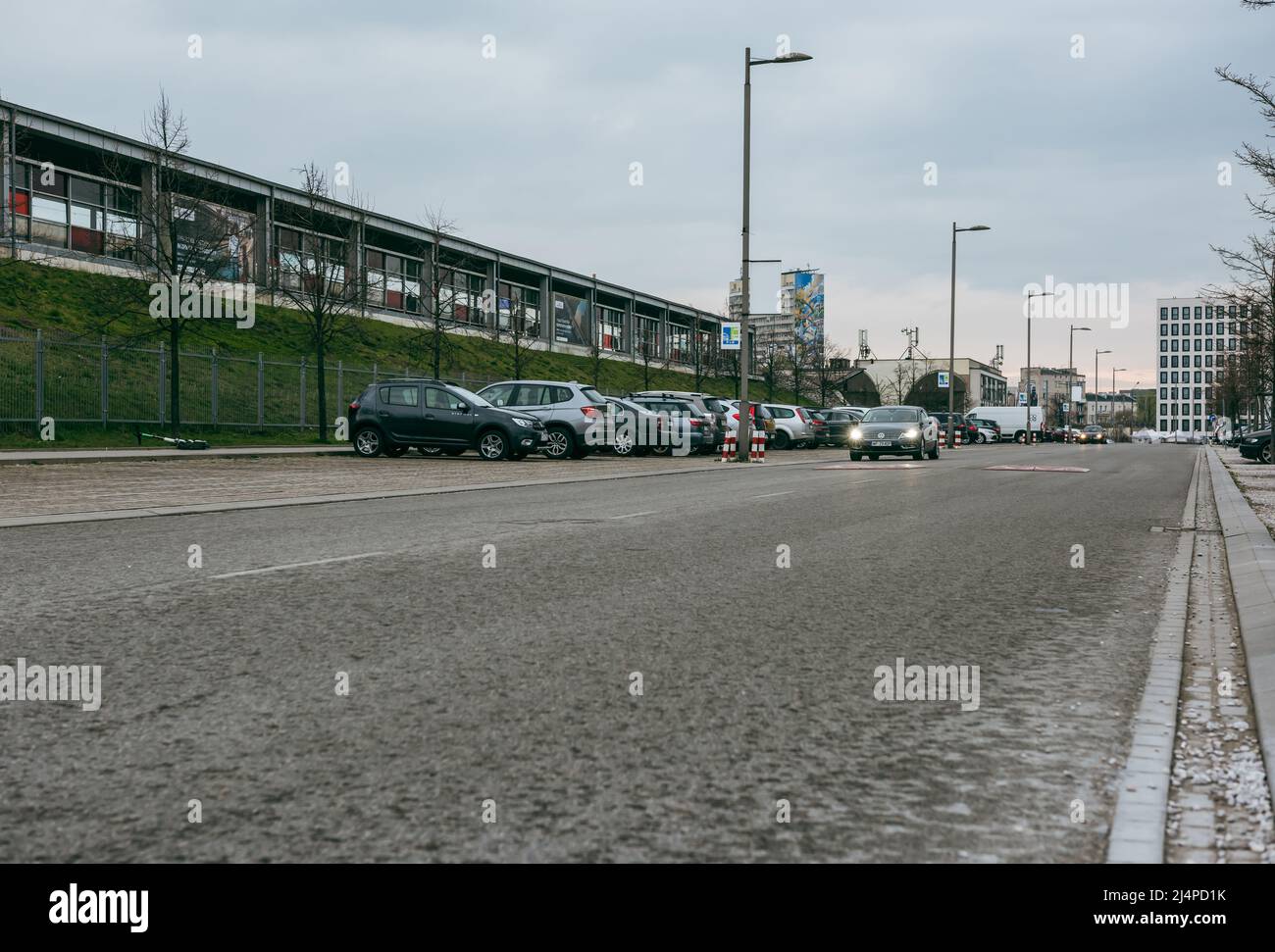 The car with the headlights on moves down the street during the day