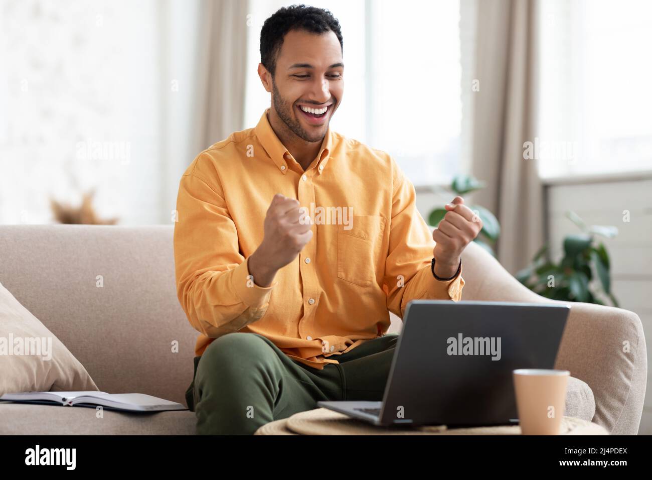 Excited man using laptop celebrating success shaking fists Stock Photo