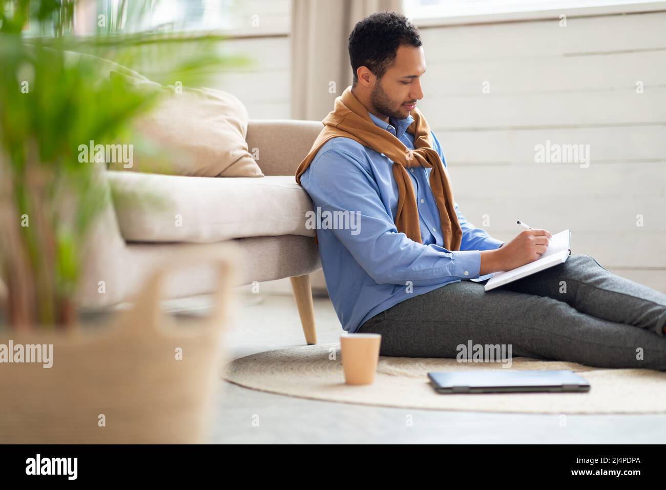 Portrait of young Arab man writing in notebook Stock Photo