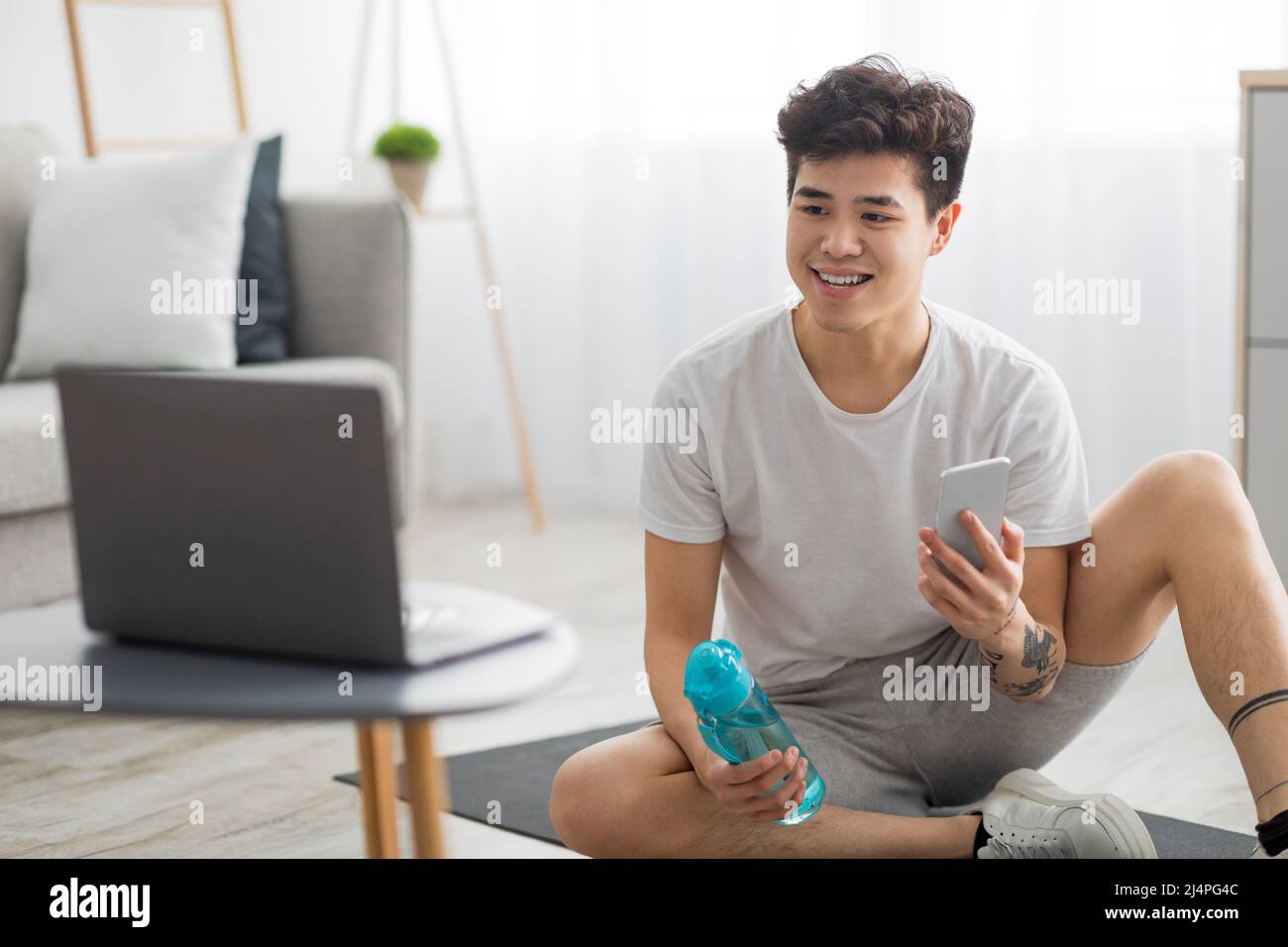 Asian guy doing exercises at home watching online tutorial Stock Photo