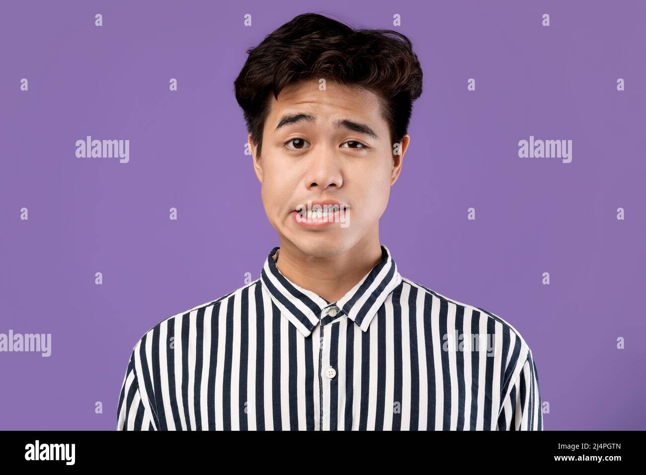 Portrait of young Asian man posing grimacing at studio Stock Photo