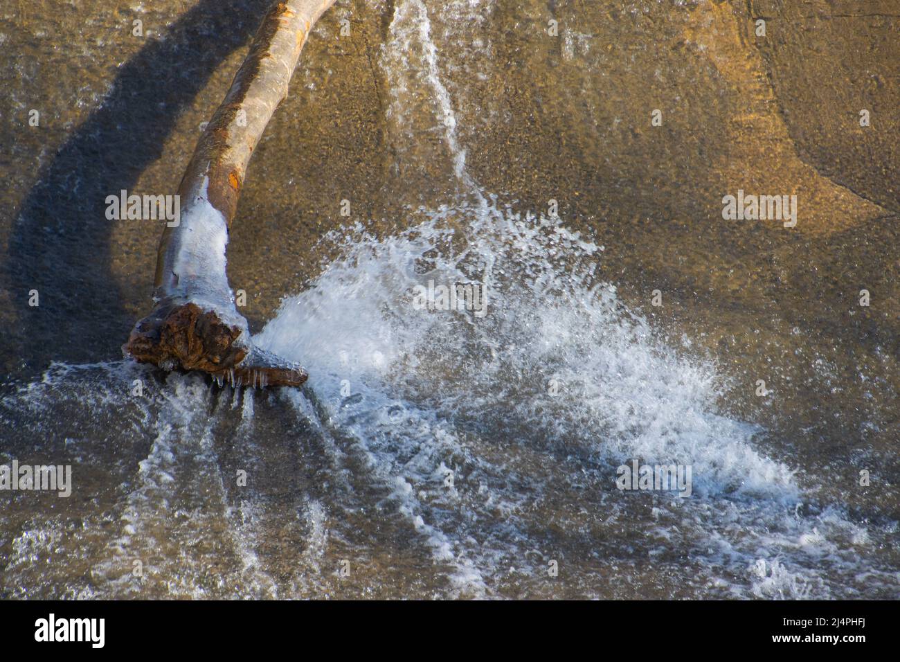 Tree trunk on a weir and water splashing Stock Photo