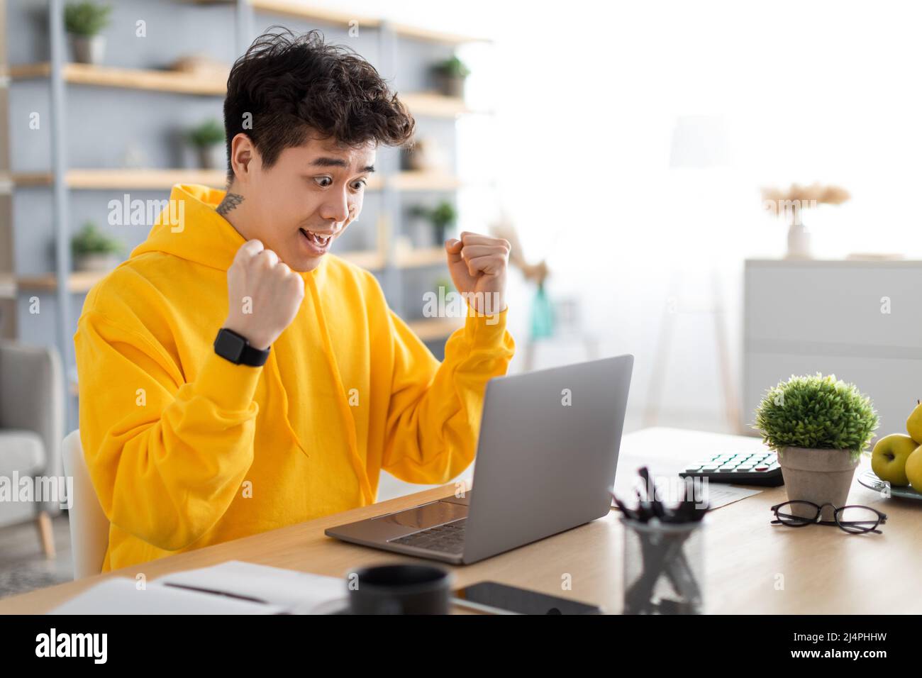 Excited Asian man using pc celebrating success shaking fists Stock Photo