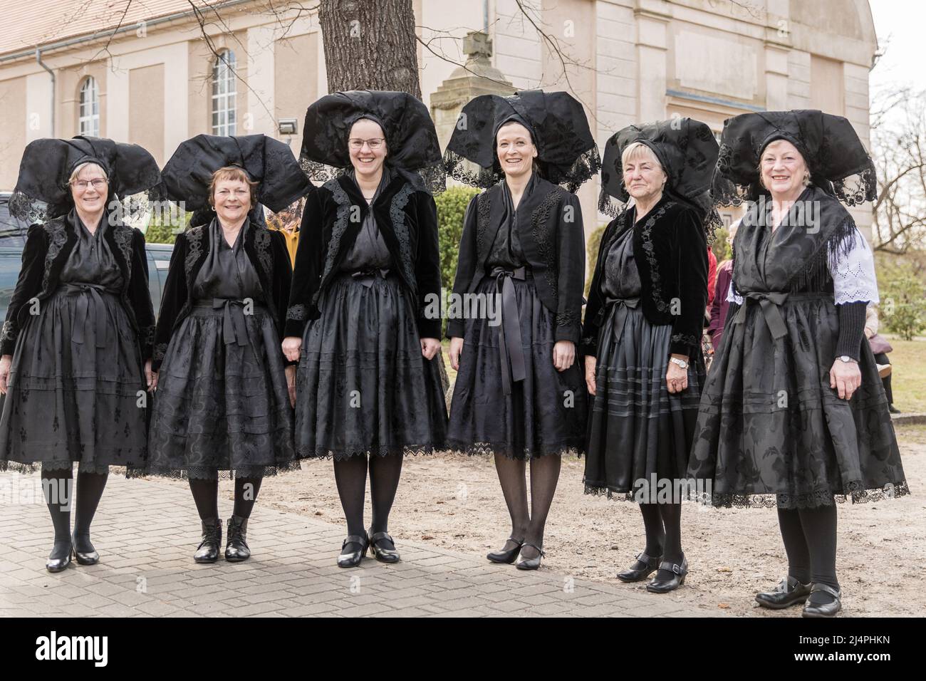 Burg, Germany. 17th Apr, 2022. Women in black traditional costumes stand in  front of the Protestant church in the Spreewald town of Burg on Easter  Sunday. They are preparing for their Easter