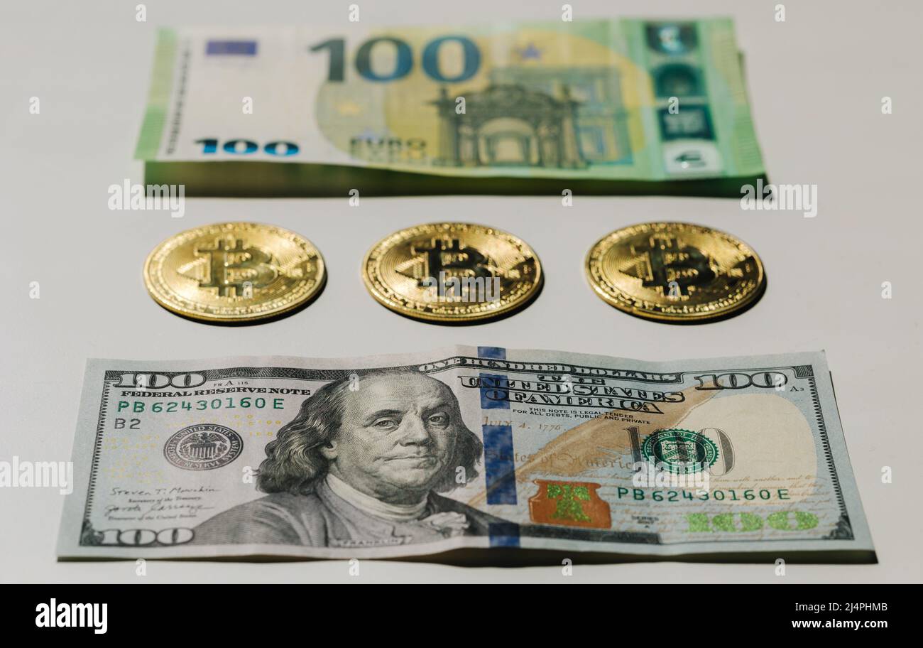Digital cryptocurrency gold bitcoin lying between US Dollar and Euro banknotes. Difference between virtual money and cash. Concept of new virtual Stock Photo