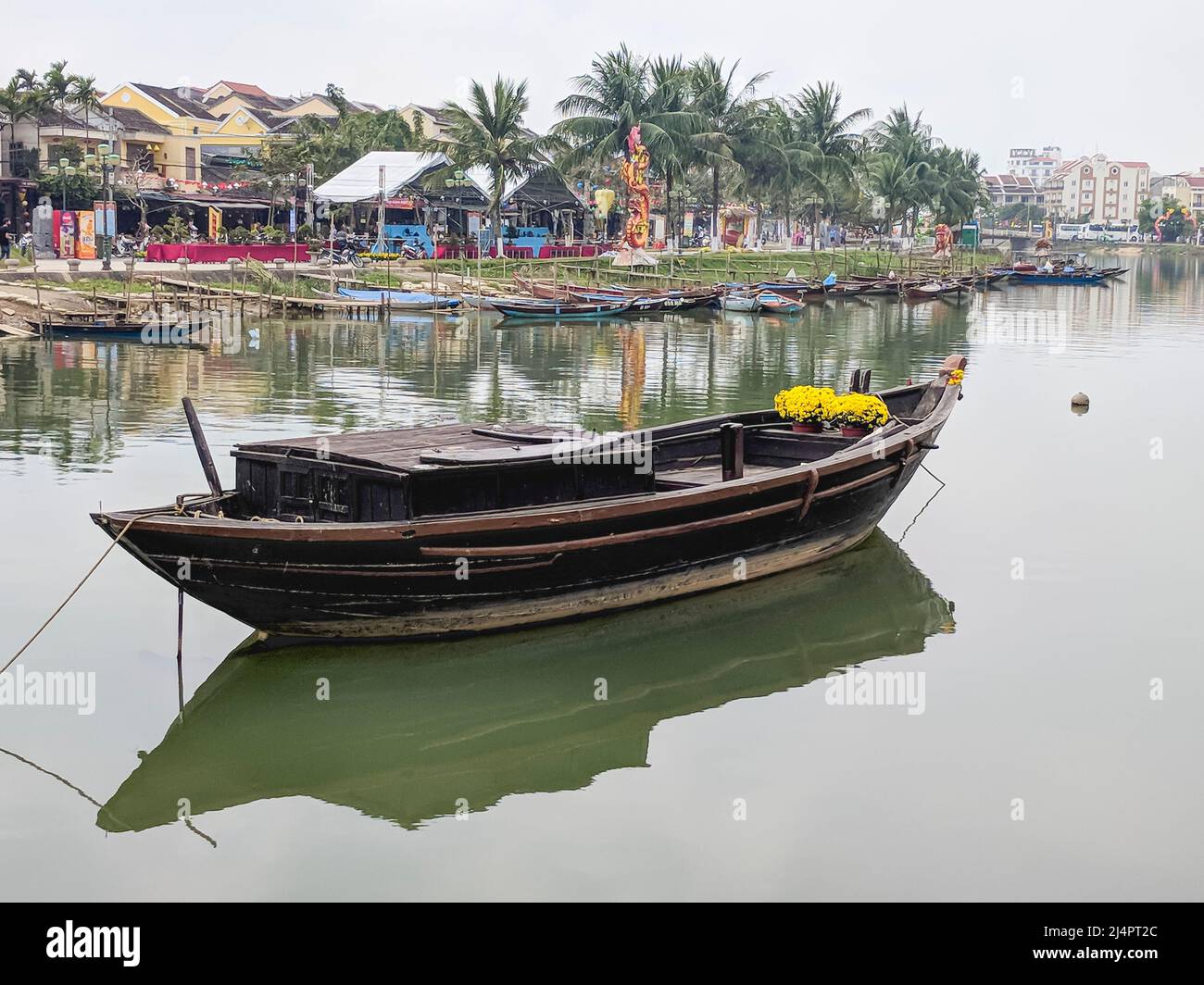 A traditional wooden boat is anchored in the Thu Bon River, Hoi An, Vietnam Stock Photo