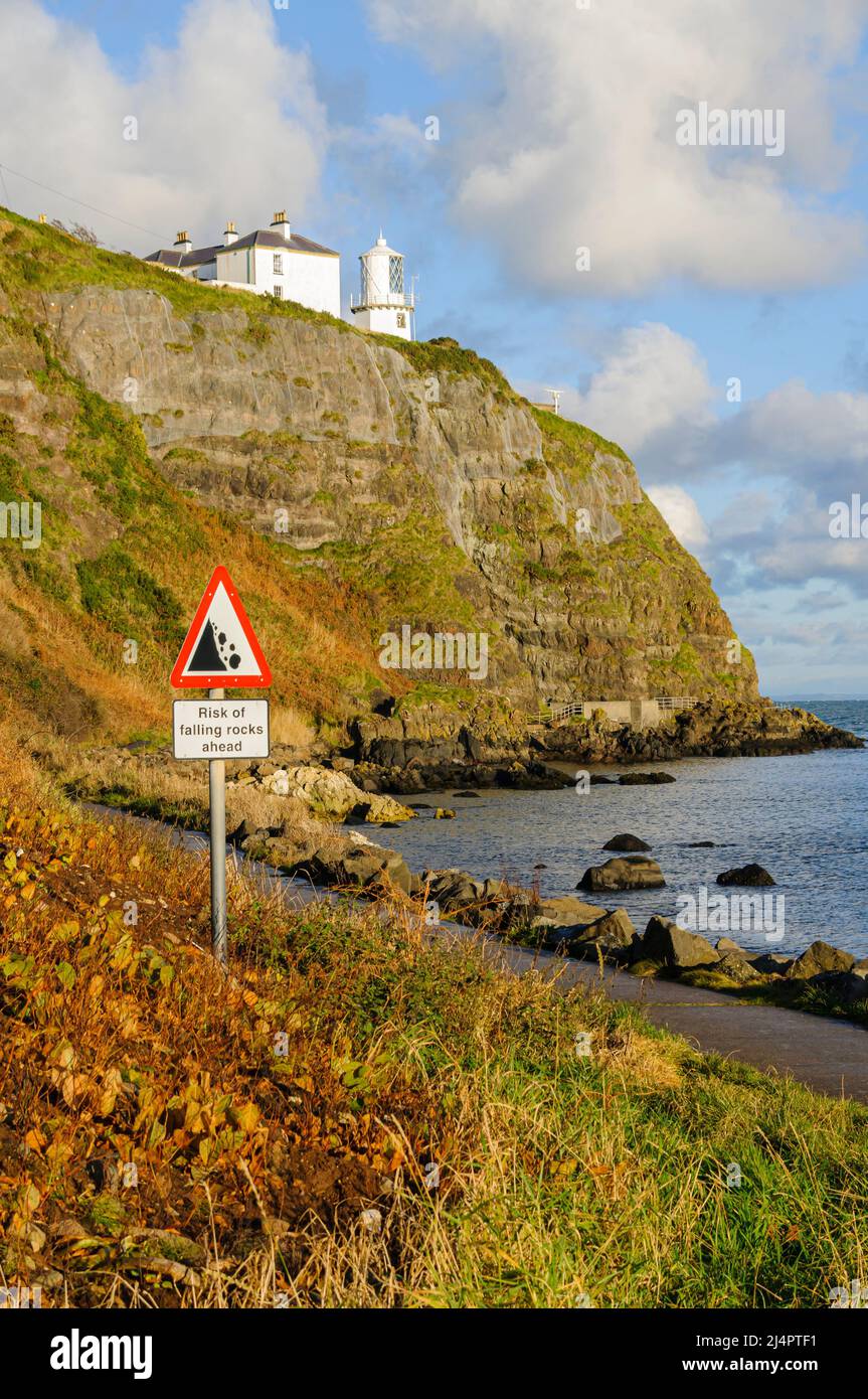 Sign warning walkers to be aware of falling rocks on a coastal path along the bottom of some cliffs. Stock Photo