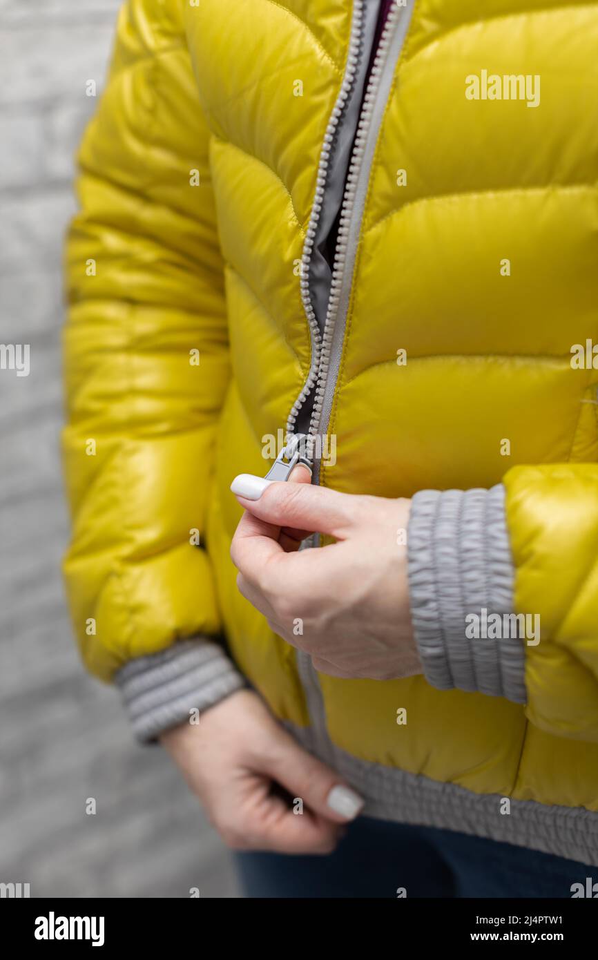 woman zips up her warm colored jacket. High quality photo Stock Photo