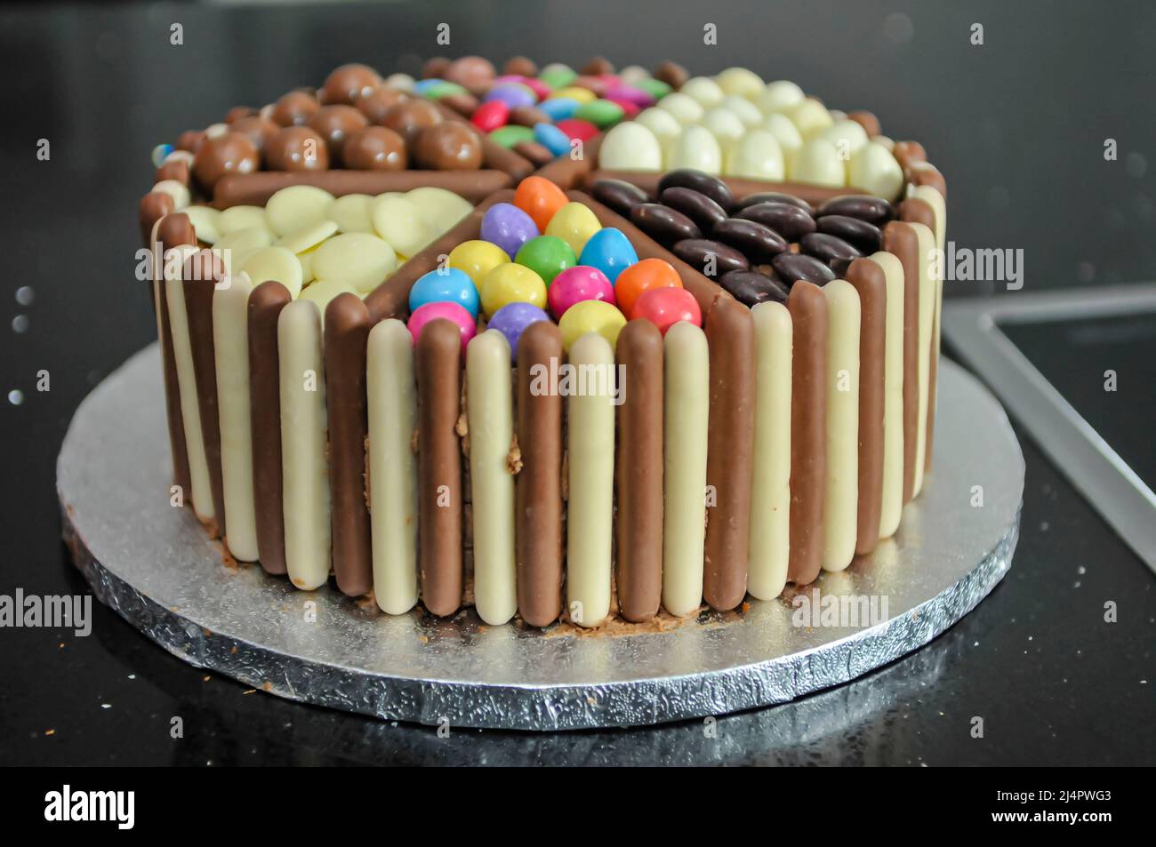 Cake decorated with chocolate fingers, white chocolate, M&Ms, Minstrels, Maltesers and Smarties Stock Photo