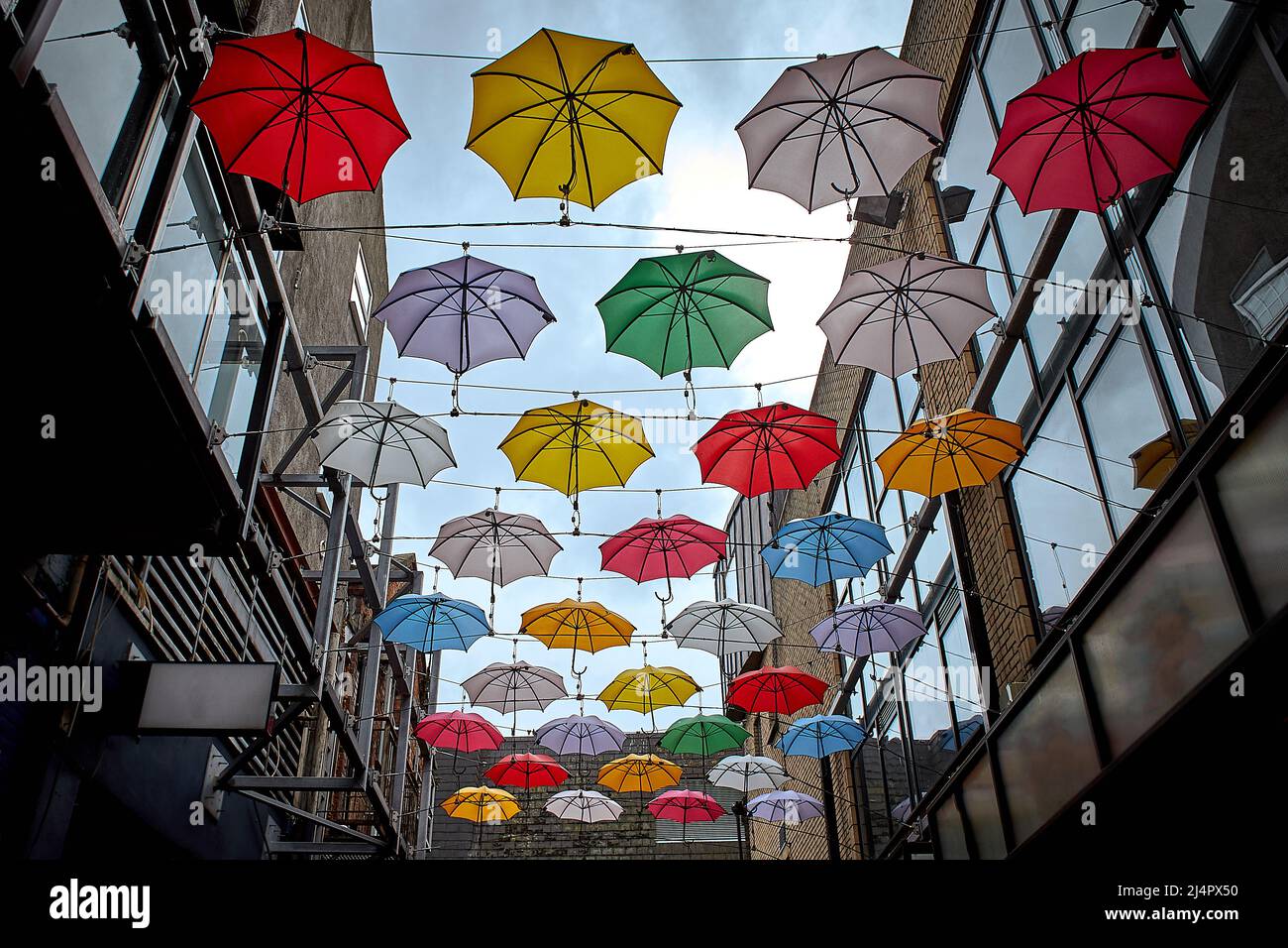 Cloudy sky and a lot of multi colored umbrellas on top of street in
