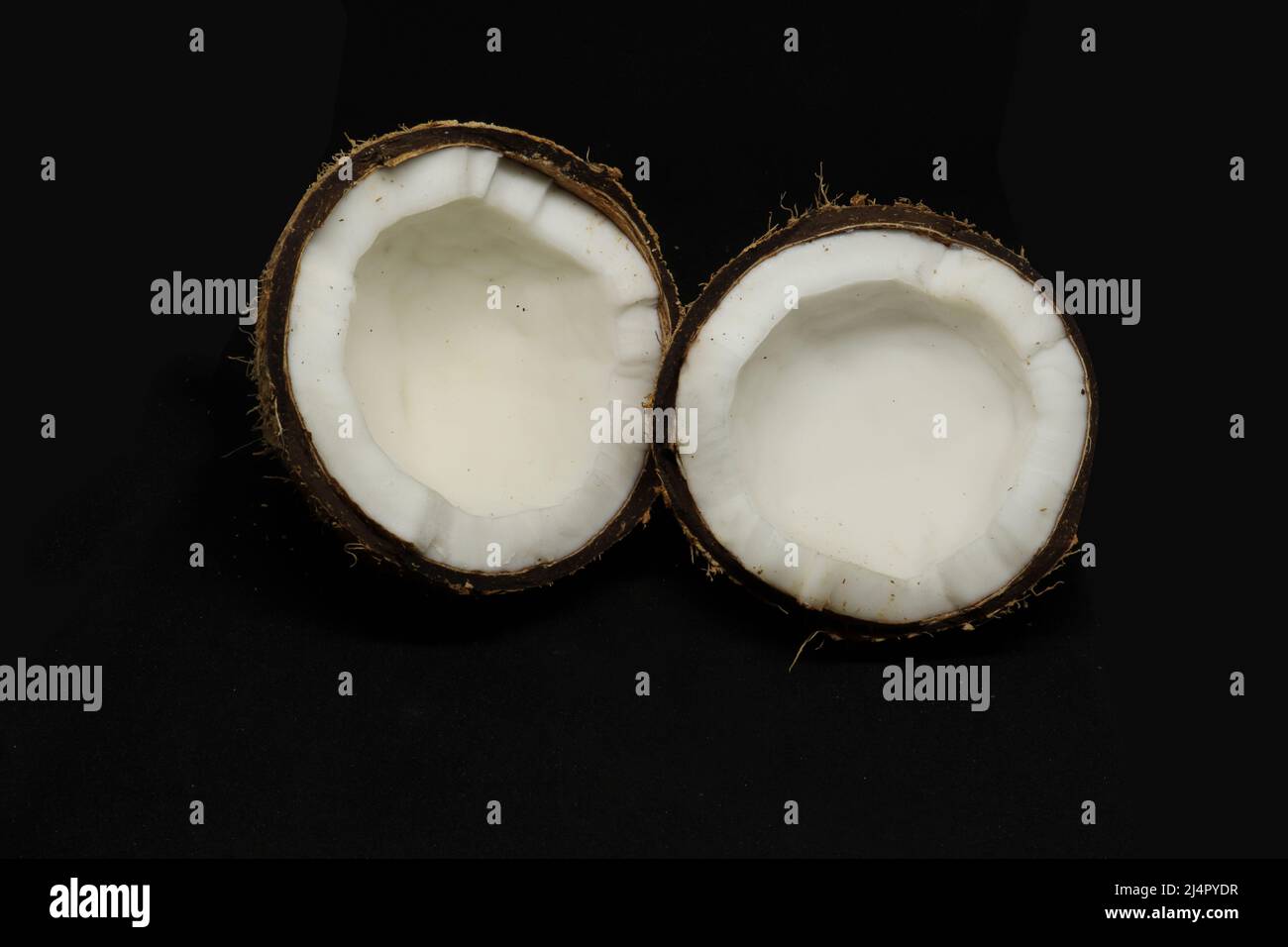 coconut cut into two pieces. on a black background Stock Photo