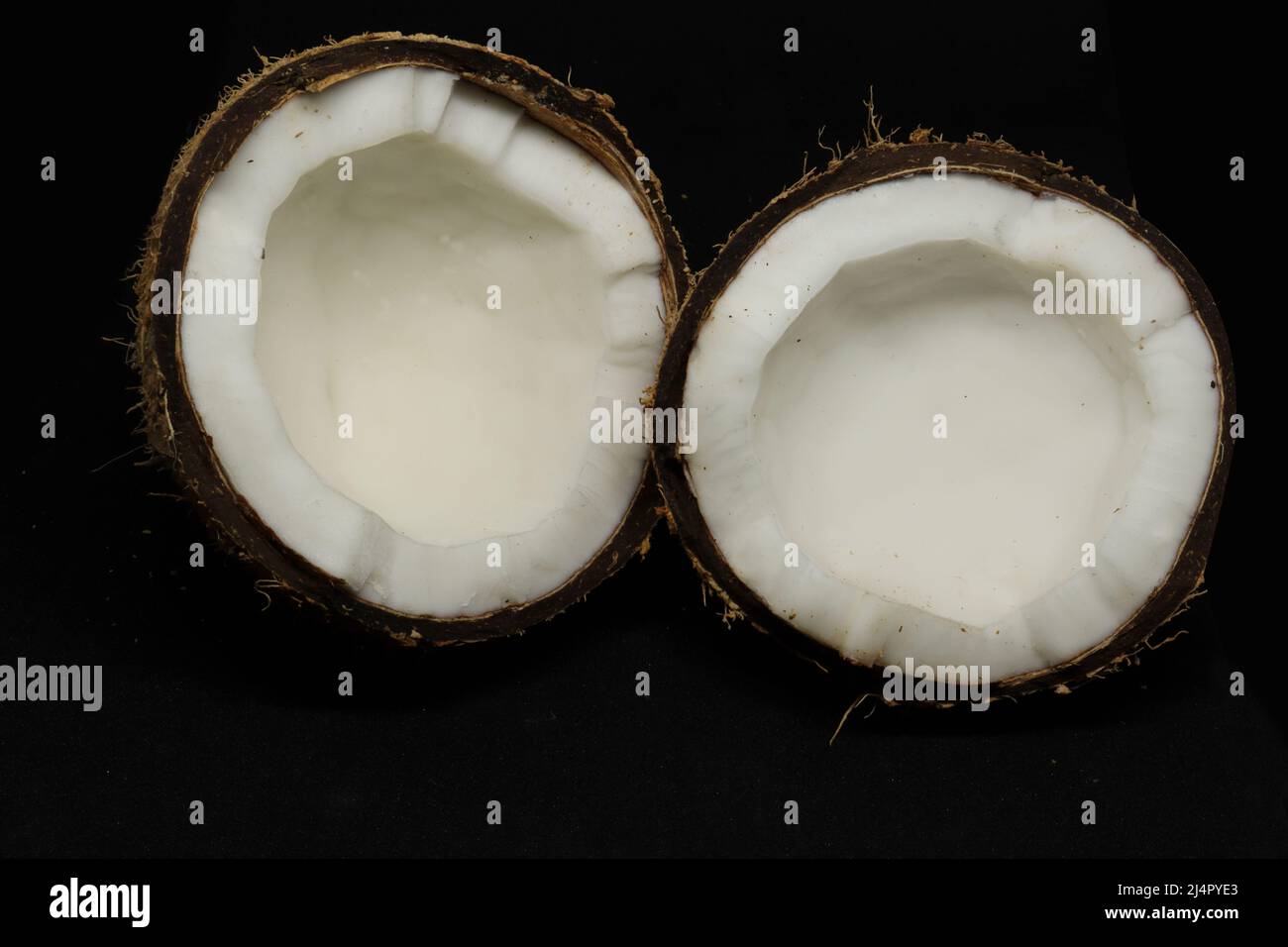 coconut cut into two pieces. on a black background Stock Photo