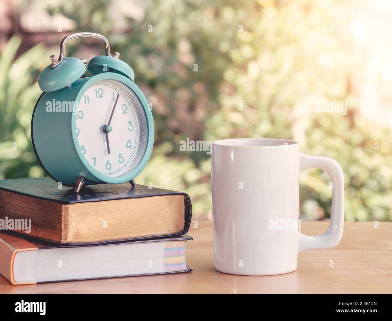 Alarm clock on workbook and textbook on the table or work desk with hot coffee in home office