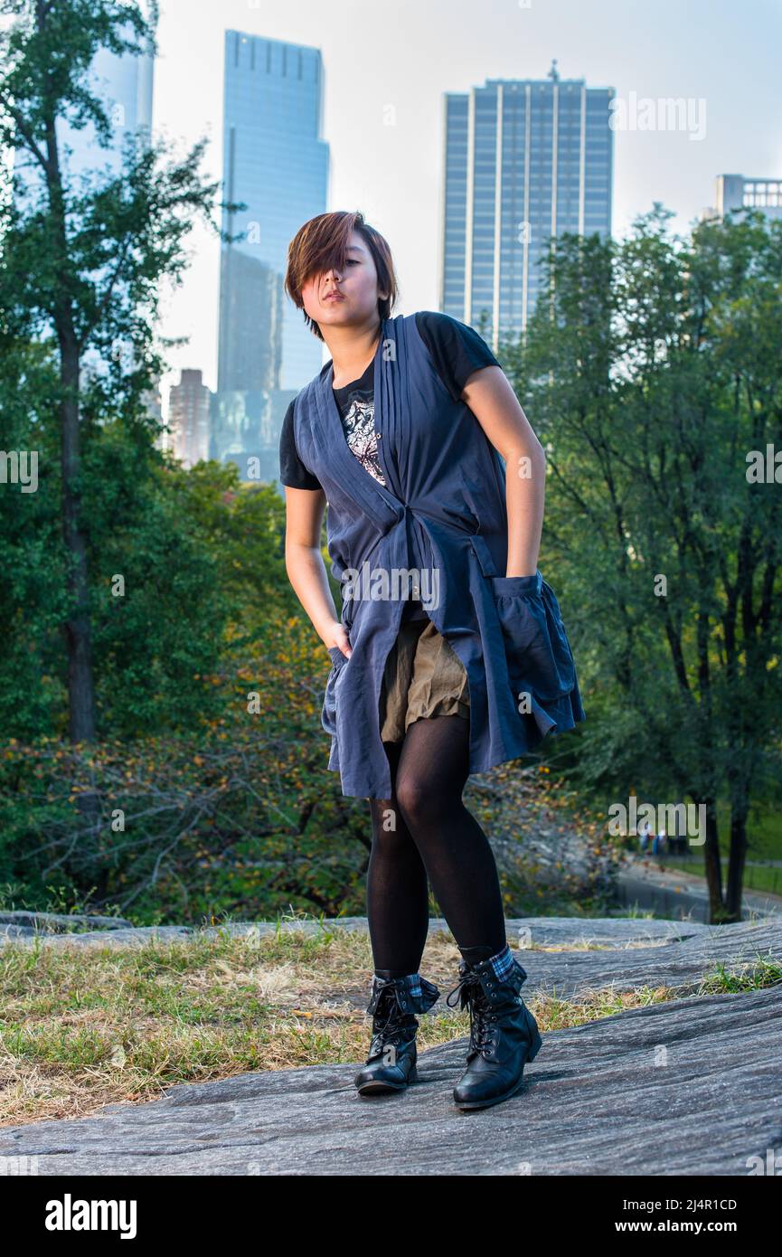 Dressing in a blue sleeveless long blouse, black leggings and