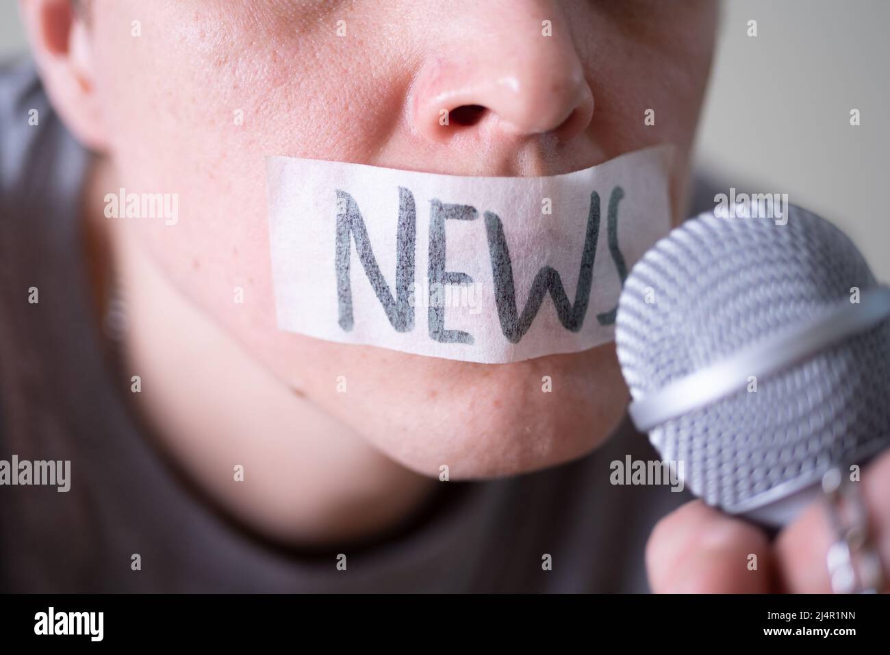 A man gags his mouth with duct tape saying news trying to speak into a