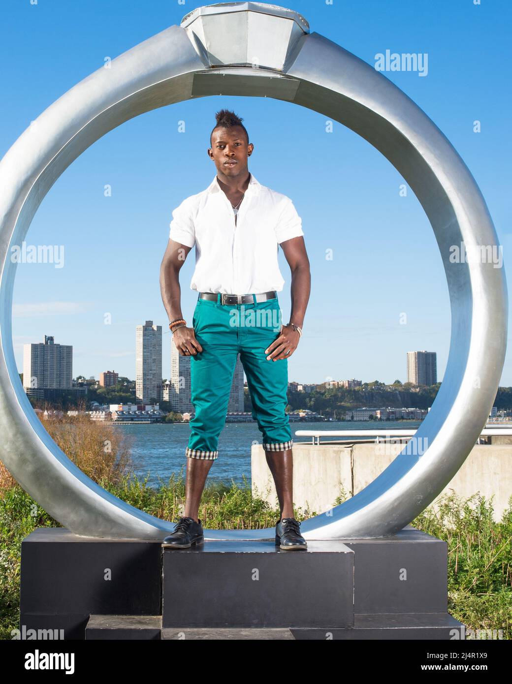 Dressing in a white shirt, green pants and black leather shoes, a young  black guy with mohawk hair is standing by a ring structure, confidently  look Stock Photo - Alamy