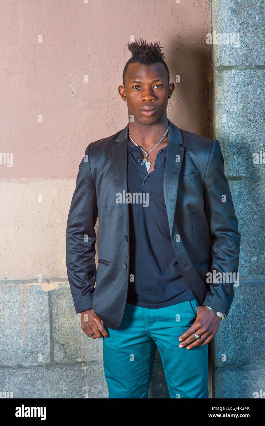 Dressing in a black blazer, green pants, a young black guy with mohawk