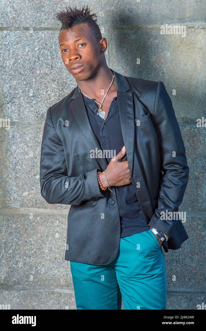 Dressing in a black blazer, green pants, a hand in his pocket, a hand