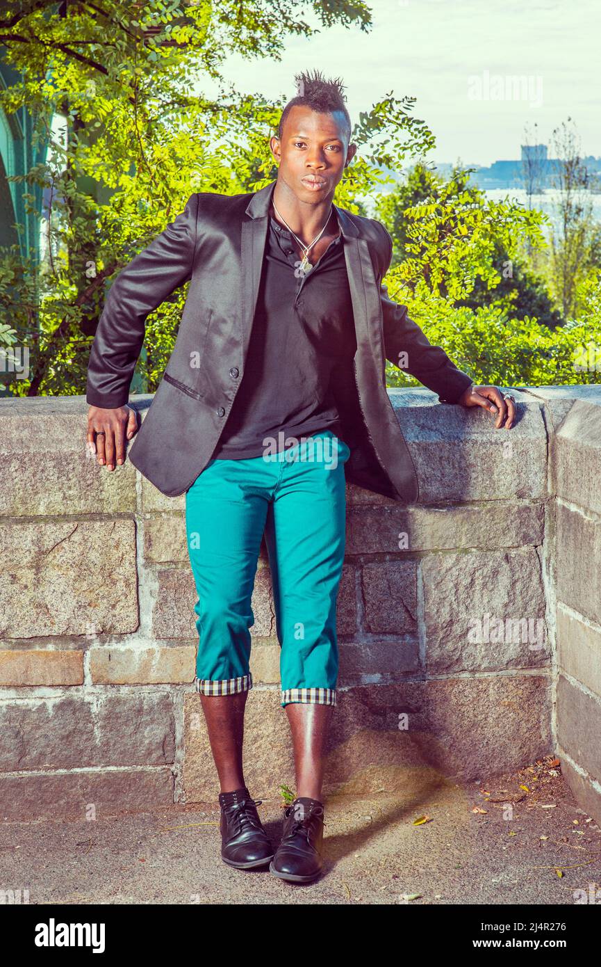 Man Relaxing Outside Dressing in a black blazer, a black undershirt, green  pants, leather shoes, a young black guy with mohawk hair is standing by a r  Stock Photo - Alamy