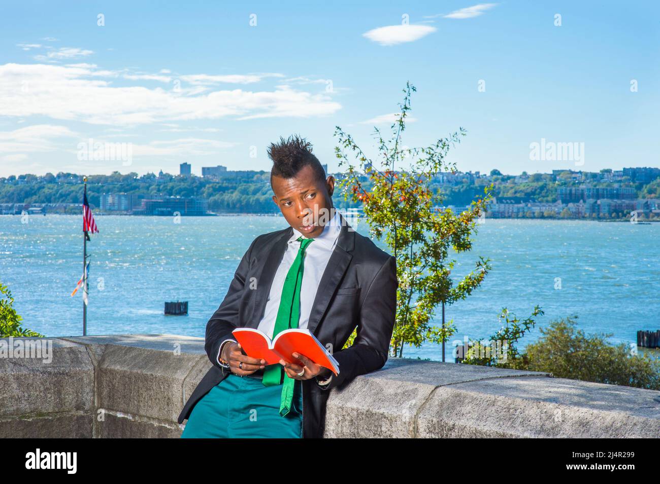 Man Reading Outside. Wearing a black blazer, green pants, a green neck