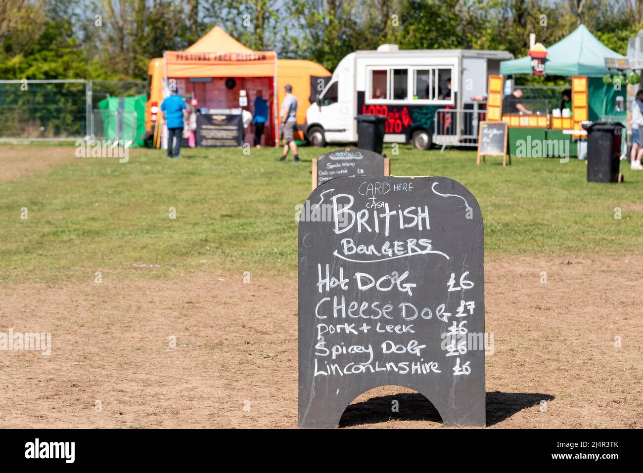 Food vendors at an outside event ready for customers. Prices on blackboard for British burgers, hot dog, cheese dog, pork, spicy dog, sausages Stock Photo