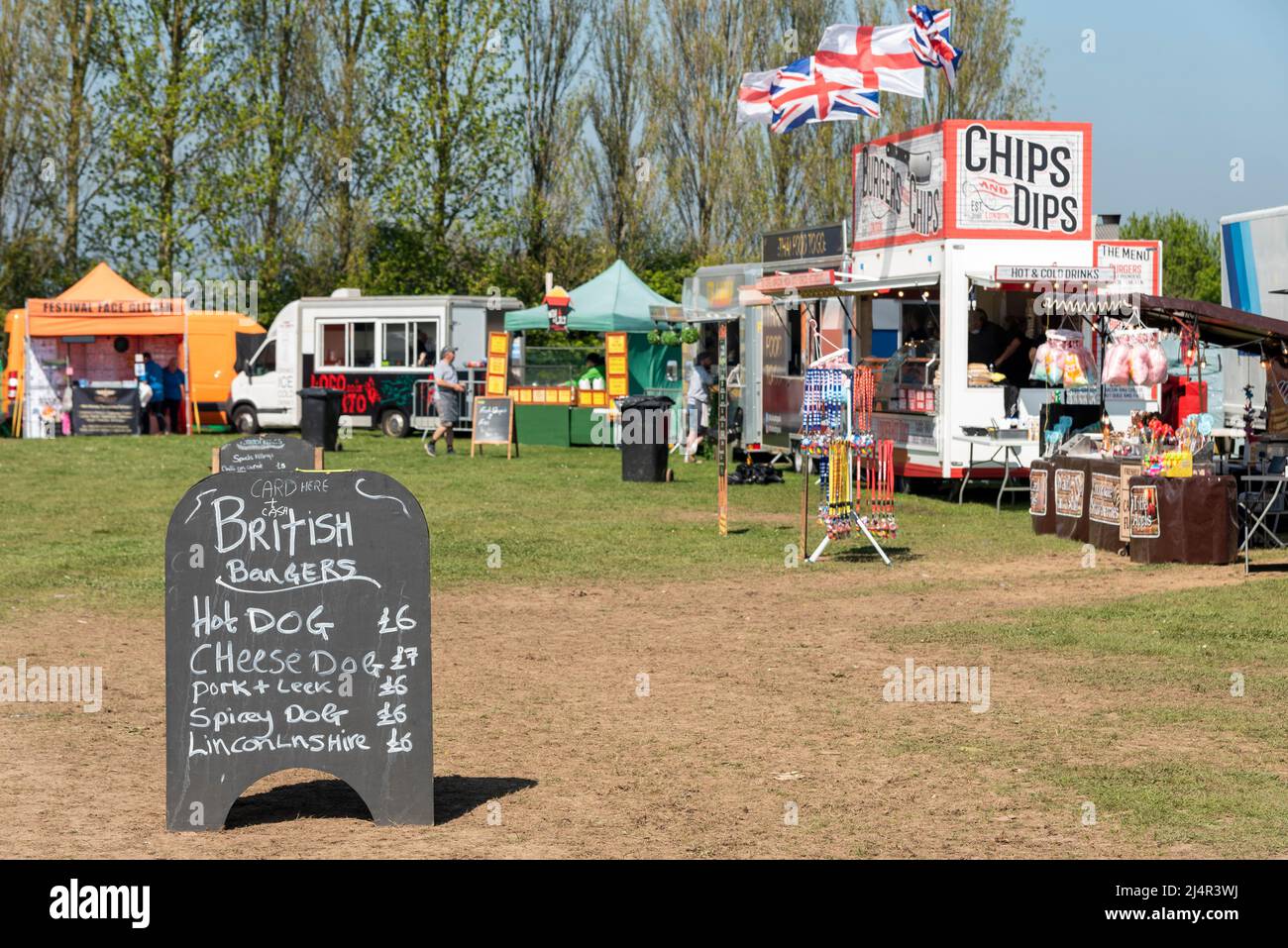 Food vendors at an outside event ready for customers. Prices on blackboard for British burgers, hot dog, cheese dog, pork, spicy dog, sausages Stock Photo