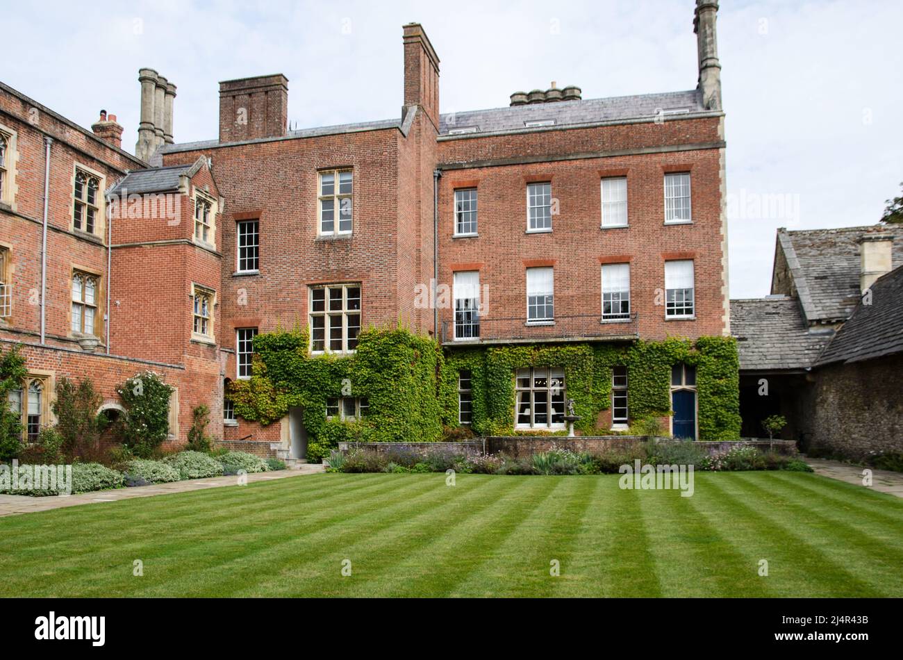 Well mown lawns and cultivated flower beds outside some historic classrooms at the famous Winchester College in Winchester, Hampshire.  Viewed on a Se Stock Photo
