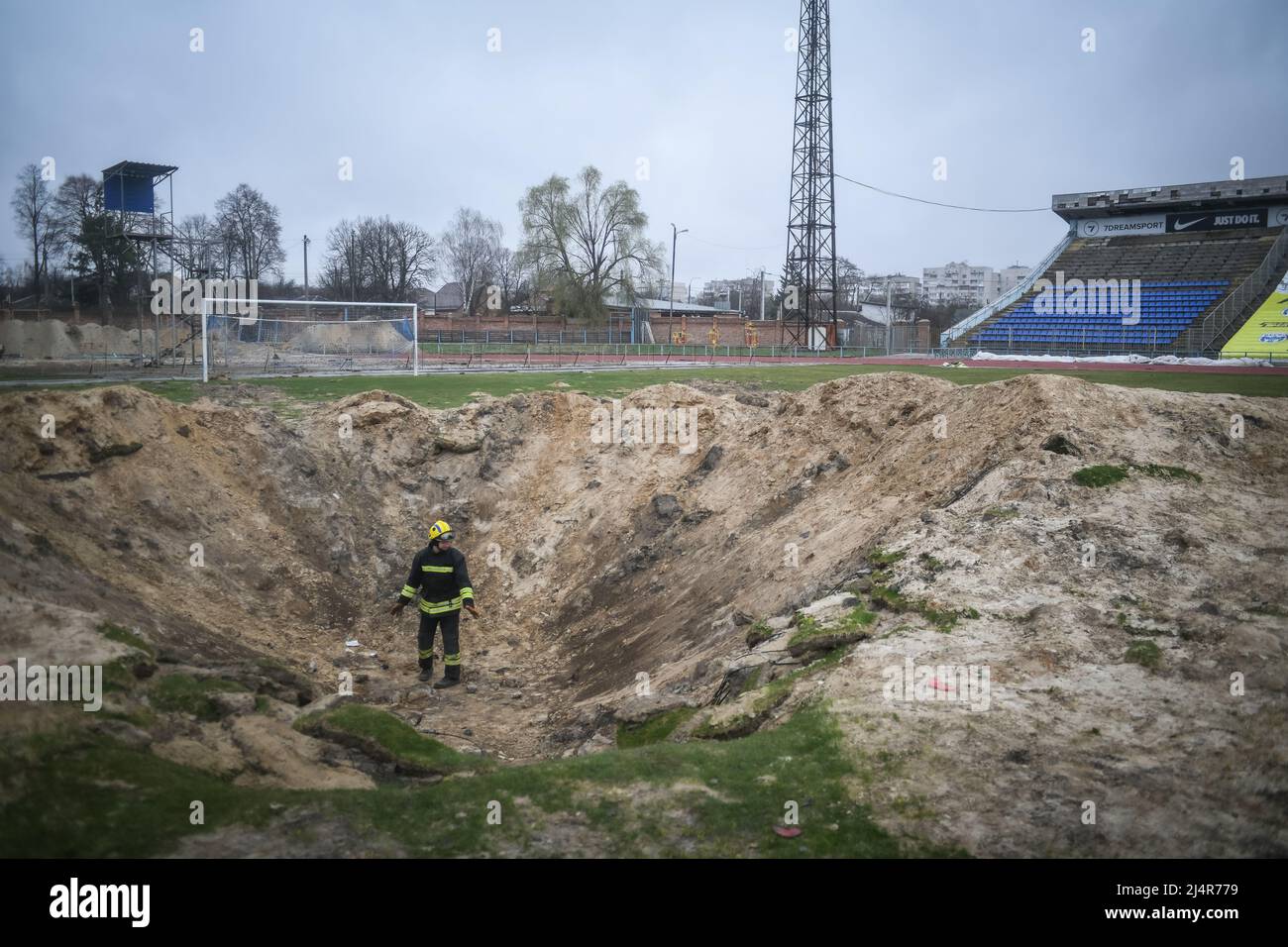 Ukraine. 16th Apr, 2022. A fire fighter inspects a crater in a football pitch at the stadium a residential area of Chernihiv, Ukraine damaged by shelling during the Russian invasion on April 16, 2022. Russian military forces entered Ukraine territory on Feb. 24, 2022. (Photo by Piero Cruciatti/Sipa USA) Credit: Sipa USA/Alamy Live News Stock Photo