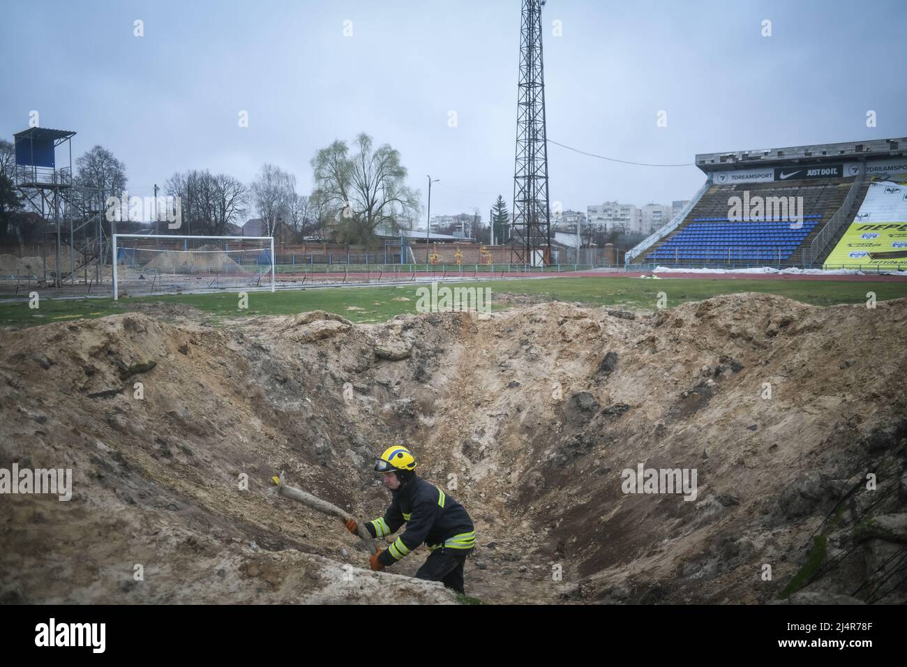 Ukraine. 16th Apr, 2022. A fire fighter inspects a crater in a football pitch at the stadium a residential area of Chernihiv, Ukraine damaged by shelling during the Russian invasion on April 16, 2022. Russian military forces entered Ukraine territory on Feb. 24, 2022. (Photo by Piero Cruciatti/Sipa USA) Credit: Sipa USA/Alamy Live News Stock Photo