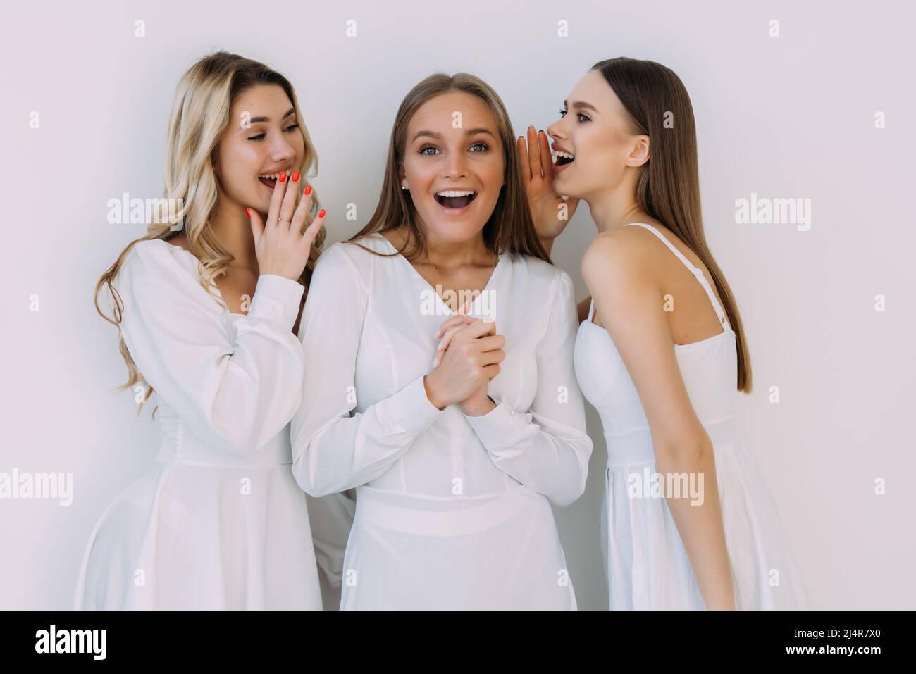 Portrait of three women standing together and talking secrets in girl's ...