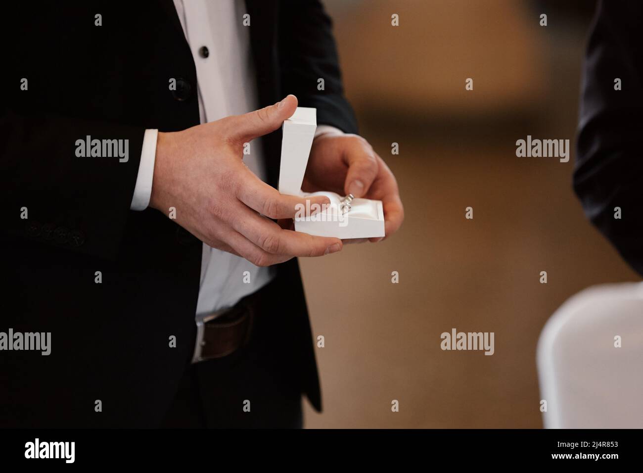The groom holds gold wedding rings in a white box for the bride in the