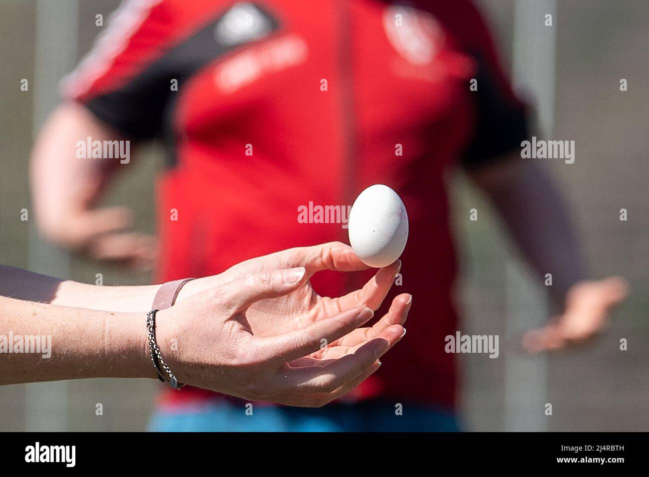 17 April 2022, Hessen, Wald-Michelbach: A participant catches an egg during the TSV Aschbach Easter egg toss. After a two-year break, the Easter egg throwing event takes place in Wald-Michelbach on the Bergstrasse. Raw eggs are thrown, which must be caught again intact. The winner is the team that achieves the greatest distance. Only eggs that are past their best-before date are used. The winning team this year threw a distance of 53 meters. Photo: Sebastian Gollnow/dpa Stock Photo