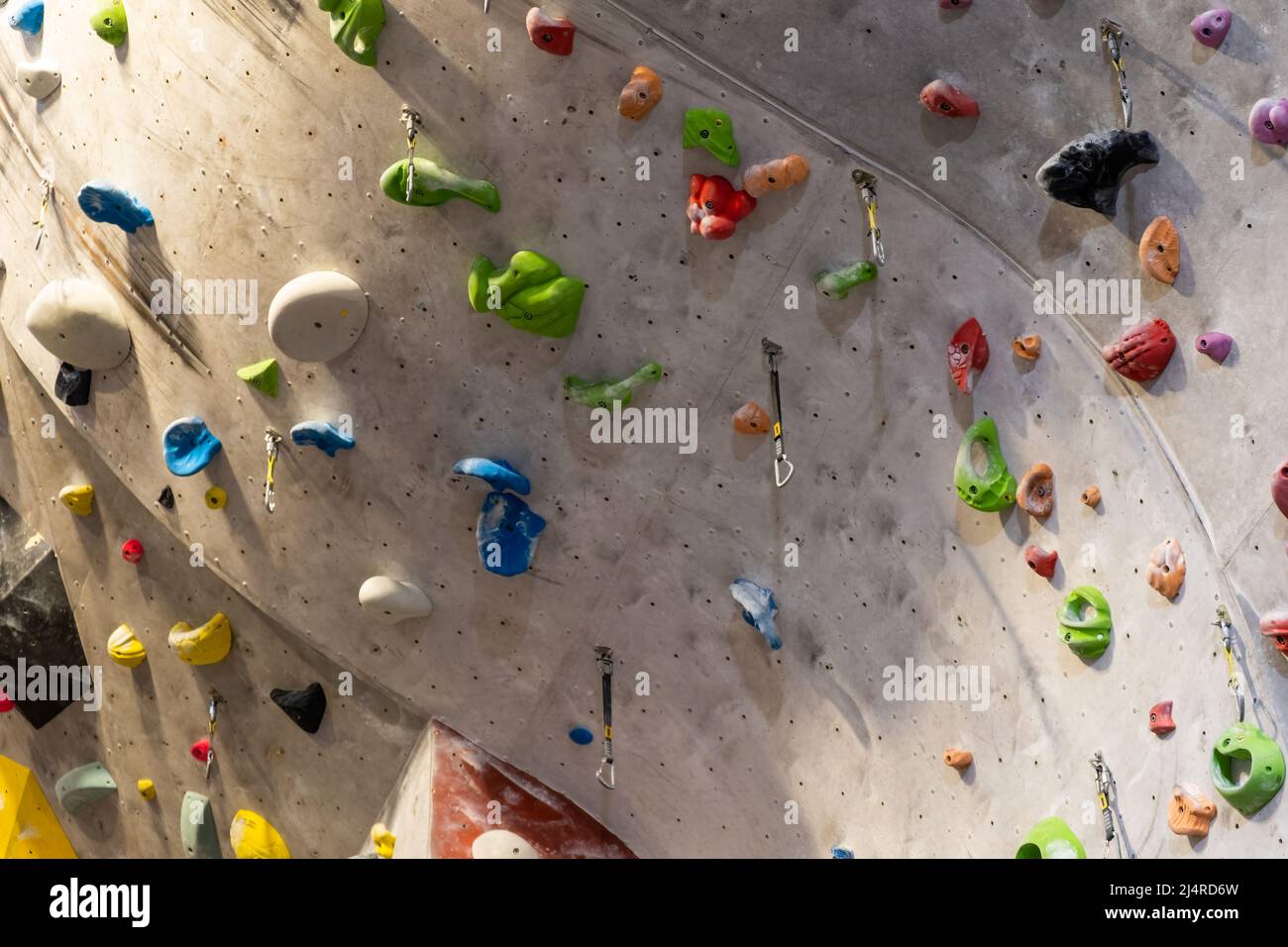 Artificial rock climbing wall with various colored grips. Stock Photo