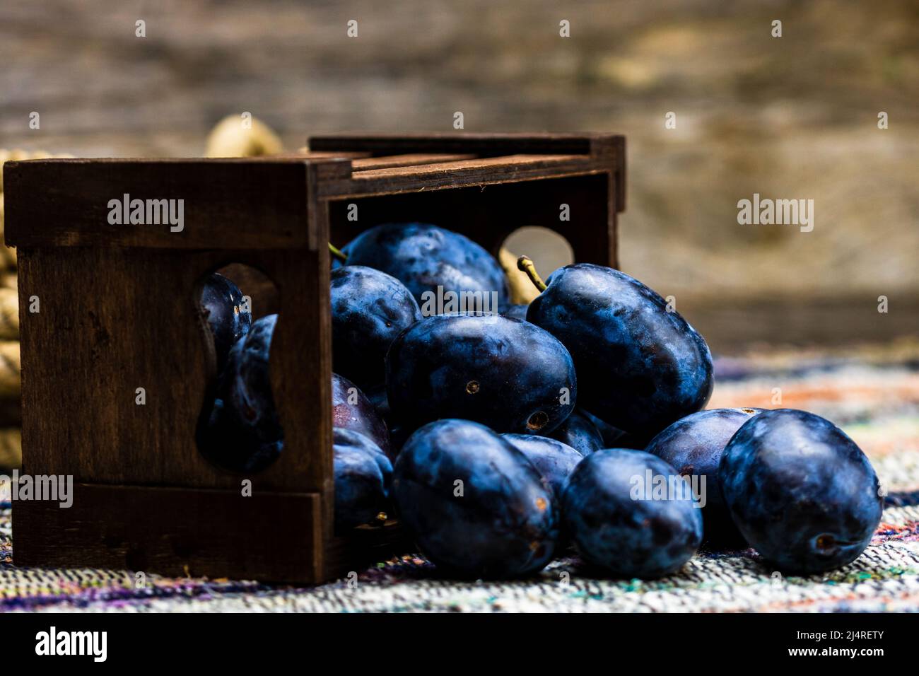 Ripe blue plums in a wooden crate in a rustic composition Stock Photo