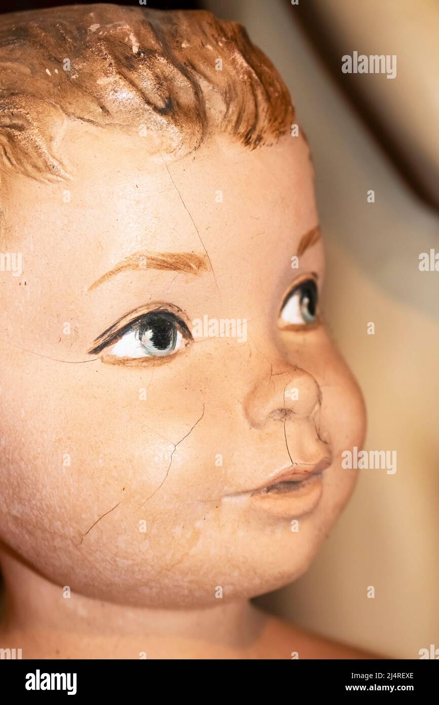 Closeup of face of cracked vintage little boy mannequin with foreground painted eye in focus Stock Photo