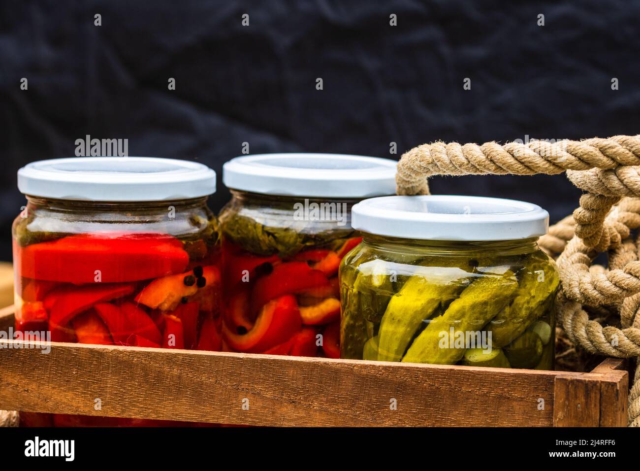 Wooden crate with glass jars with pickled red bell peppers and pickled