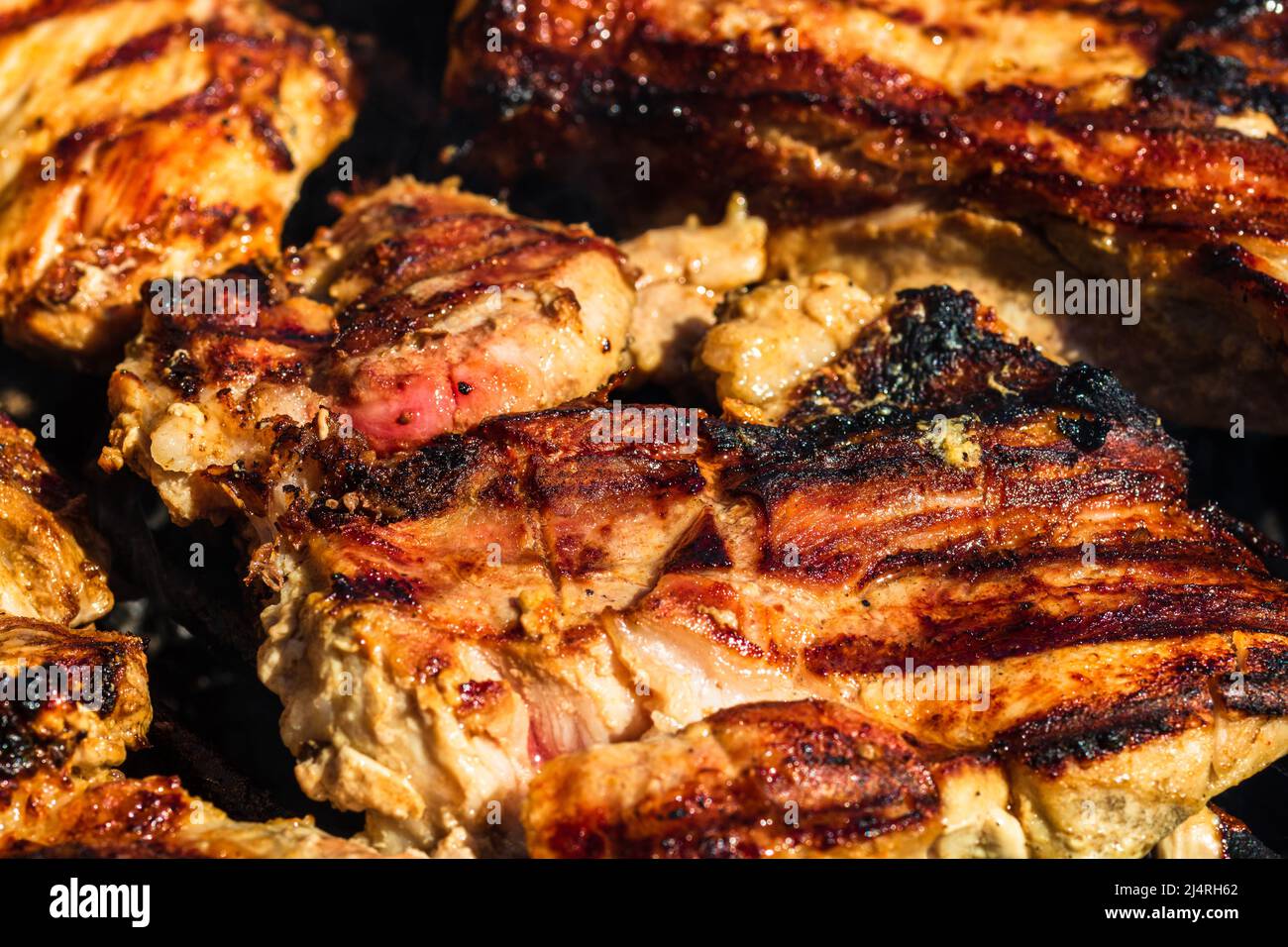 Chicken and pork steak grilled on a charcoal barbeque. Top view of