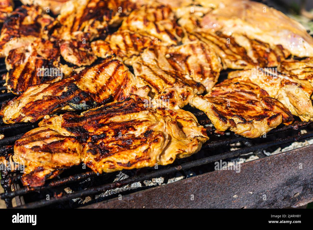Chicken and pork steak grilled on a charcoal barbeque. Top view of
