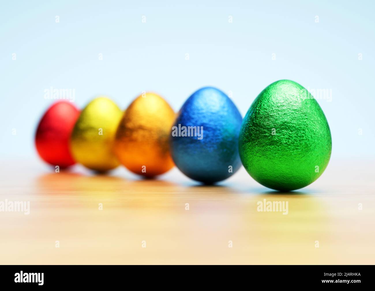 Chocolate easter eggs with shiny Red, yellow, orange, blue and green foil on white background. Close-up. Stock Photo