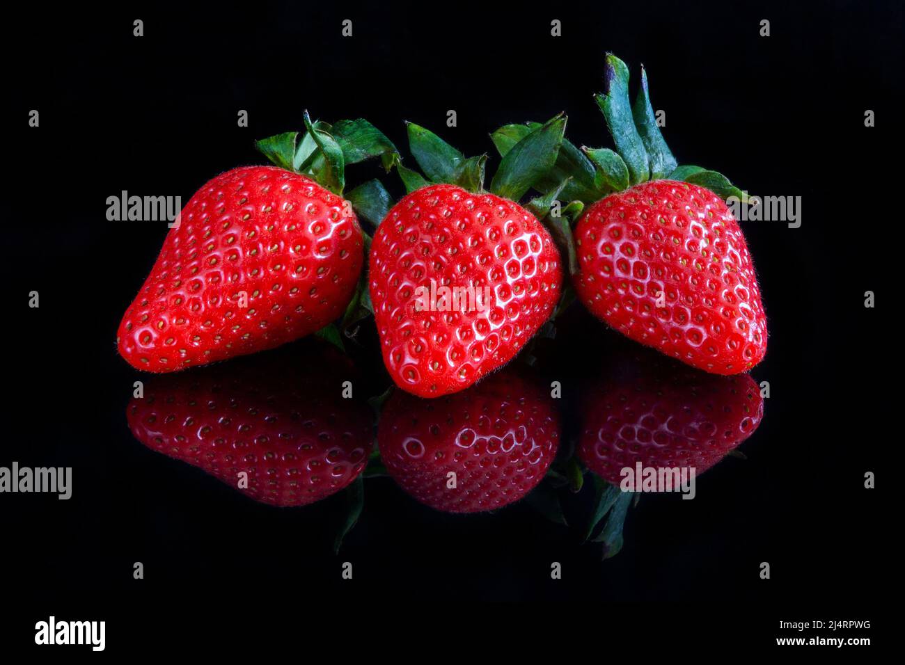 Fresh strawberries over reflective black background Stock Photo