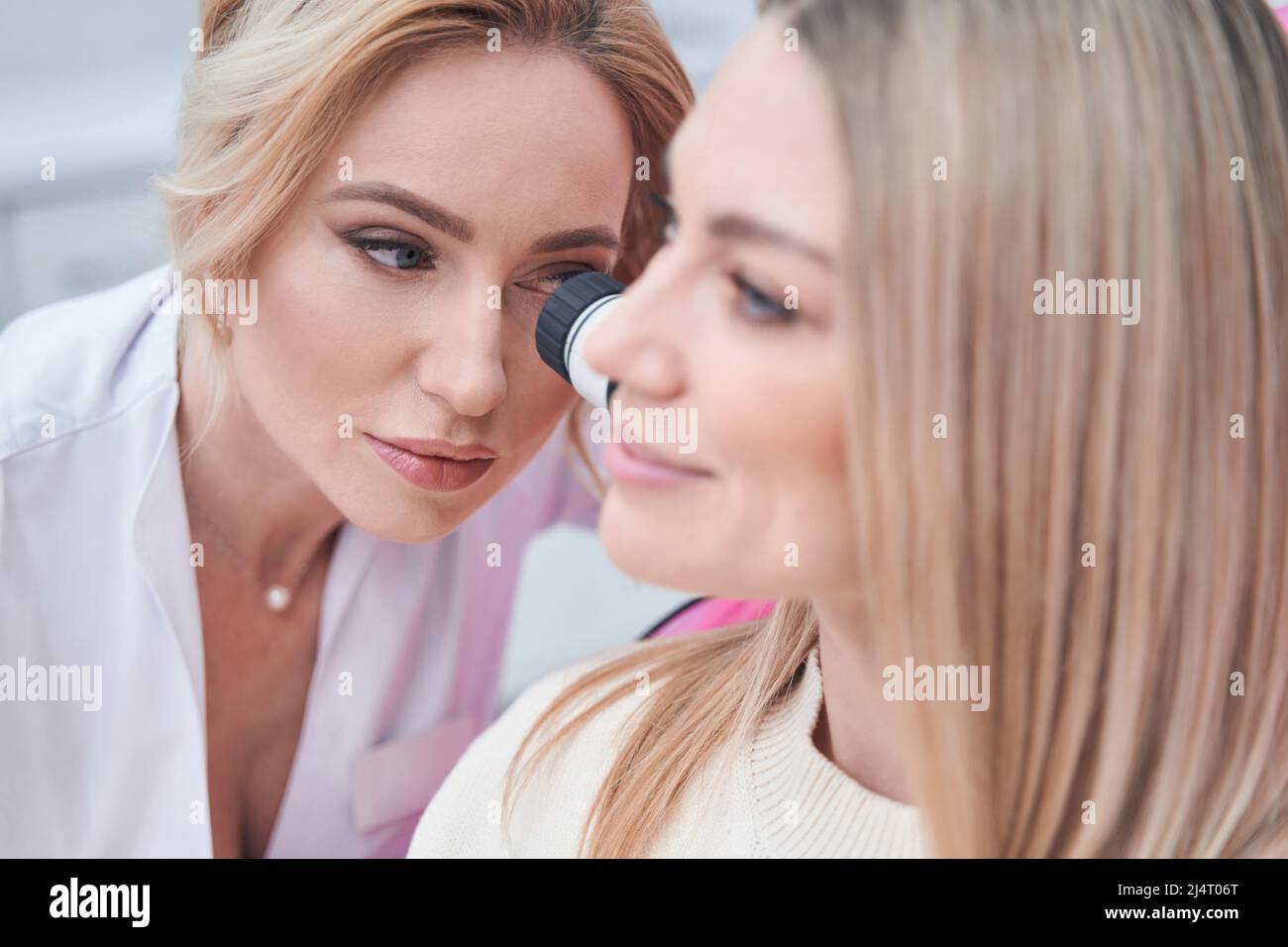 Dermatologist using dermoscopy equipment for cutaneous examination Stock Photo