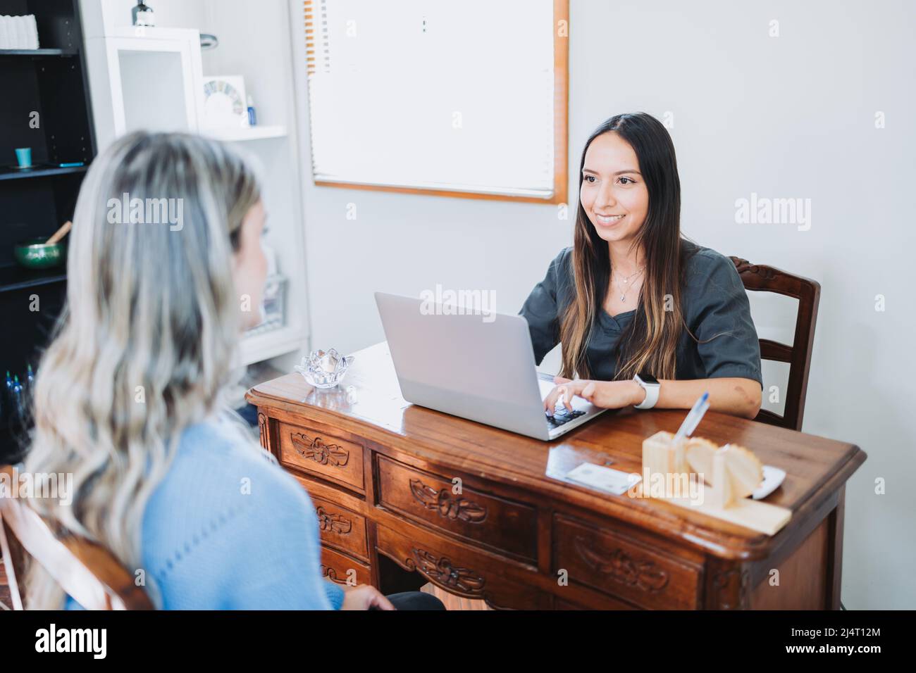 Young latin therapist taking data from an unrecognizable patient before a massage session. Healthcare consulting. Stock Photo