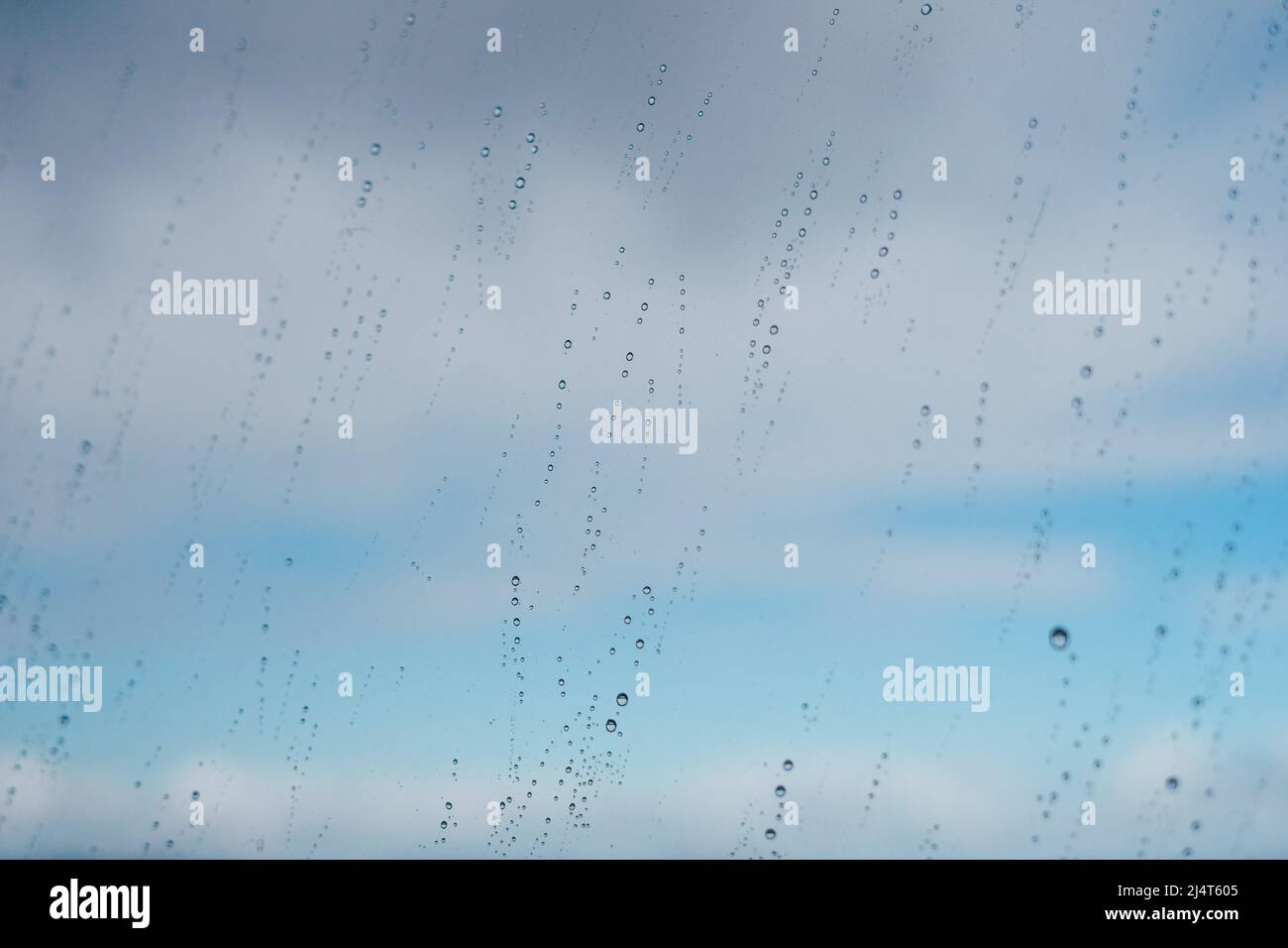 Raindrops on a window against the blue sky with clouds Stock Photo