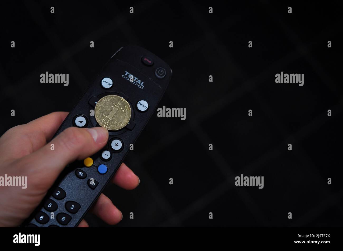 hand with remote control and Ukrainian coin management of money. translation from Ukrainian: Ukraine, one hryvnia Stock Photo