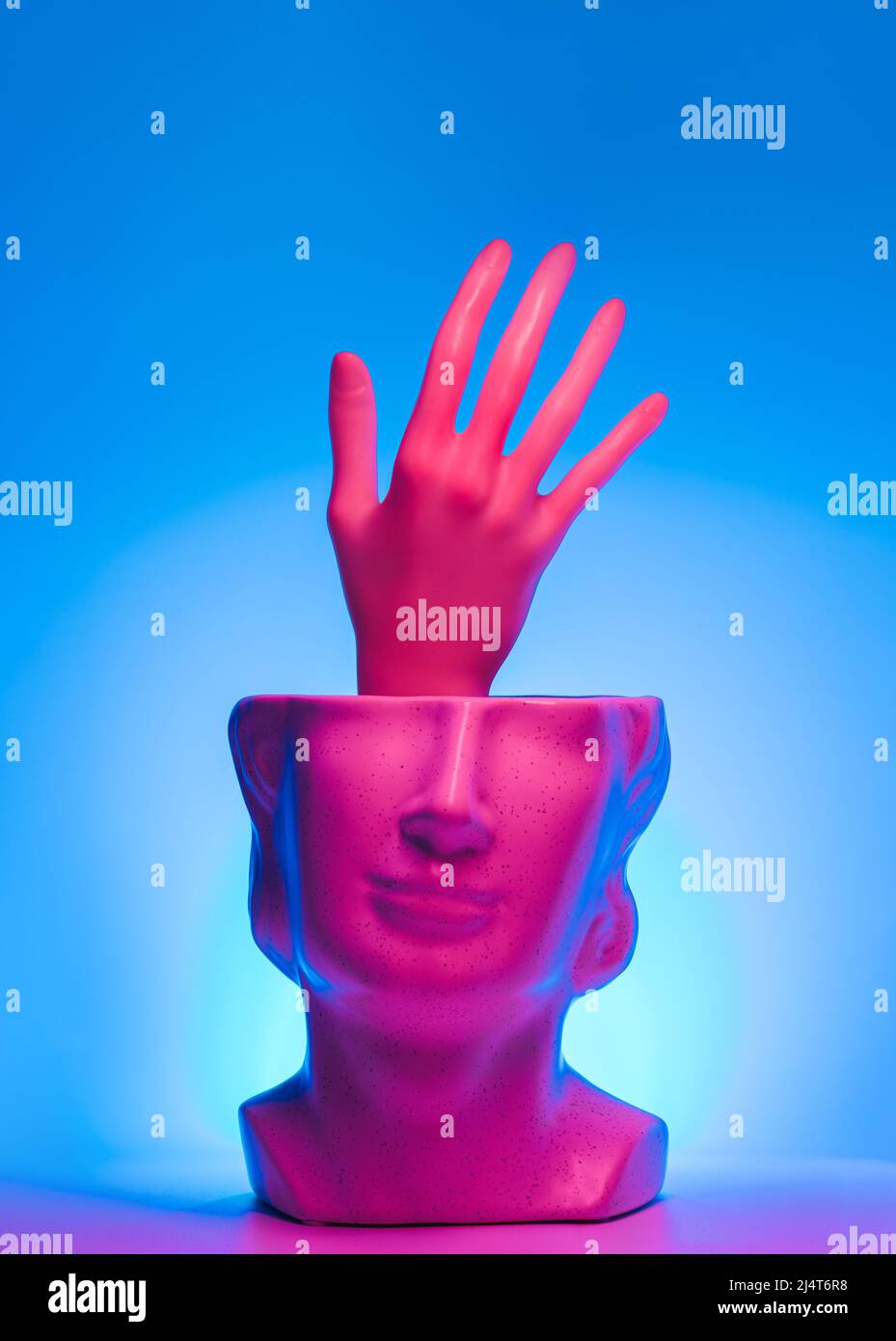 Hand reaching out from statue head and magenta teal led lights. Neon, help surreal concept. Stock Photo